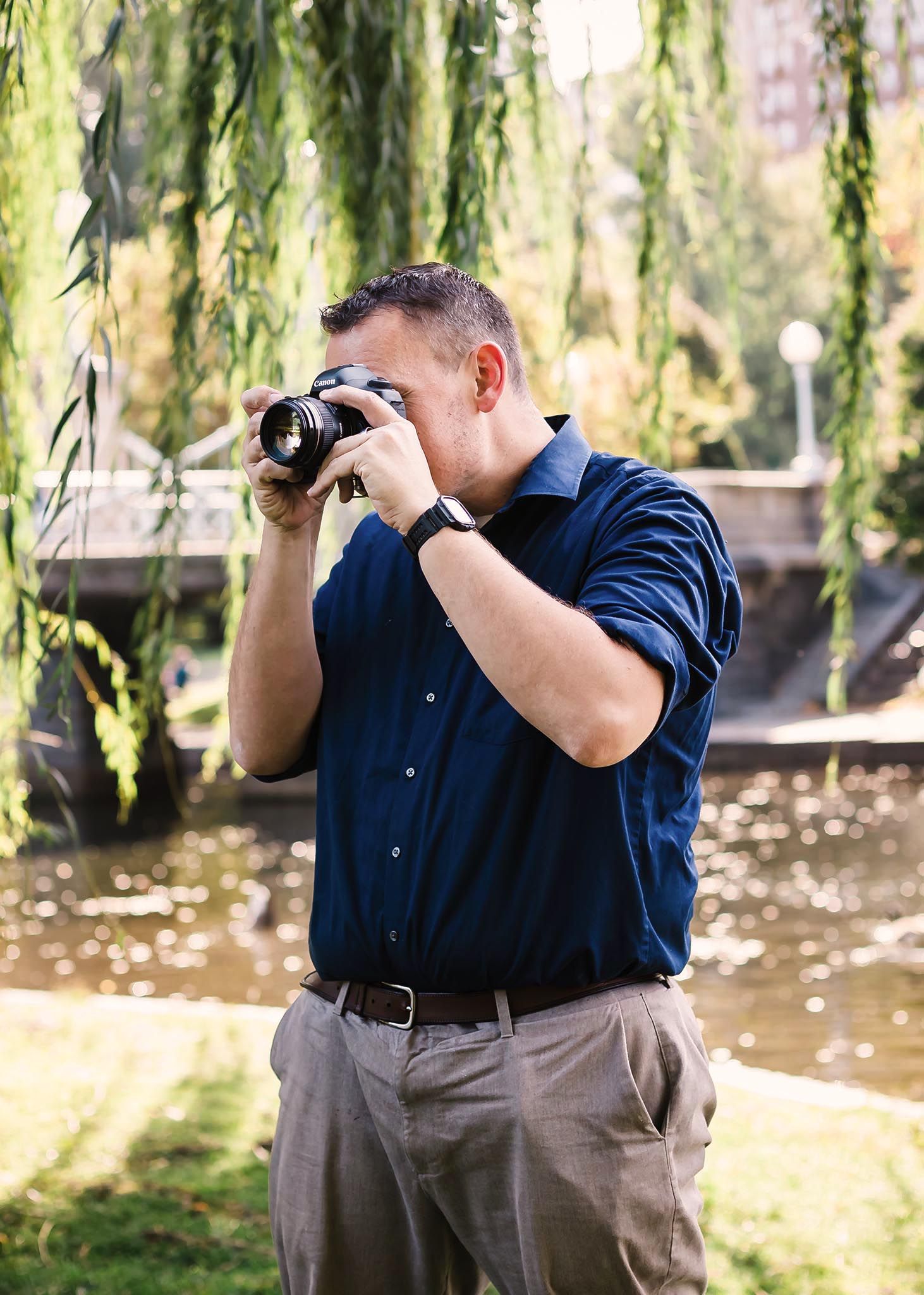 Boston wedding photographer Gregory Hitchcock photographing in the Boston Public Garden, wearing a navy shirt and capturing images beneath h