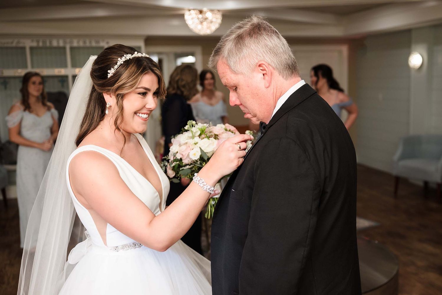 Image of a candid moment where the bride helps her father fix his boutineer right before the wedding ceremony.