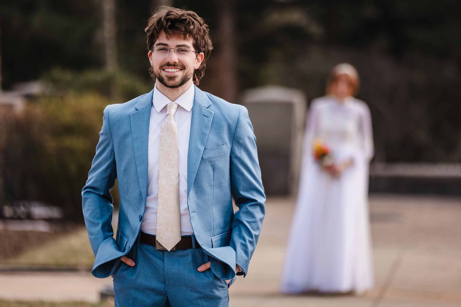 Groom standing alone for a formal portrait, smiling at camera with hands in pockets. Elopement at Boston Massachusetts Temple, Belmont, MA