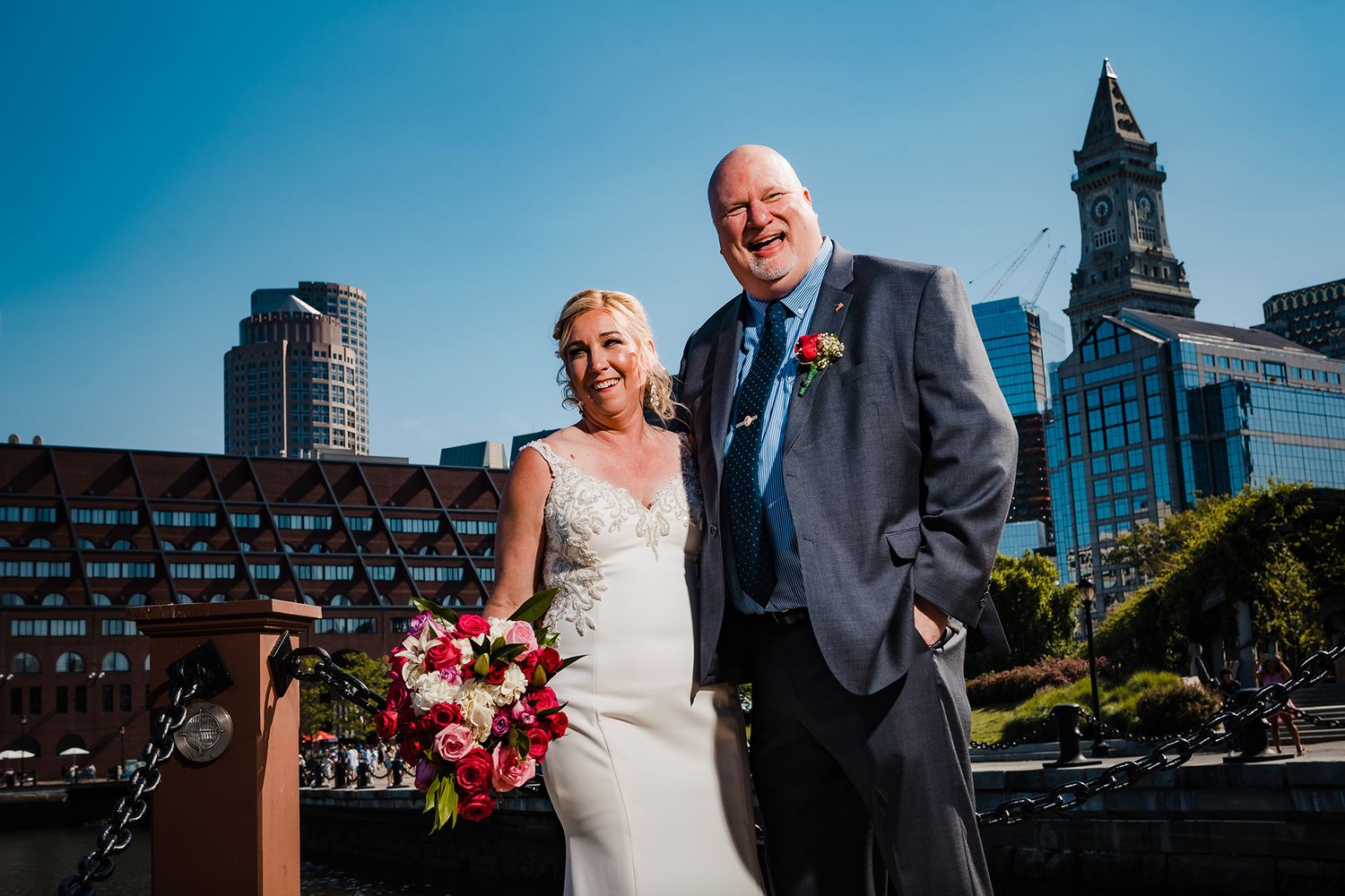 The bride and groom welcome guests to their reception while standing in Christopher Columbus Park in Boston