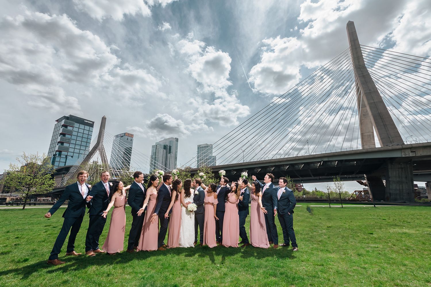 The entire bridal party cheers the bride and groom on in a passionate kiss during a portrait at Paul Revere Park.