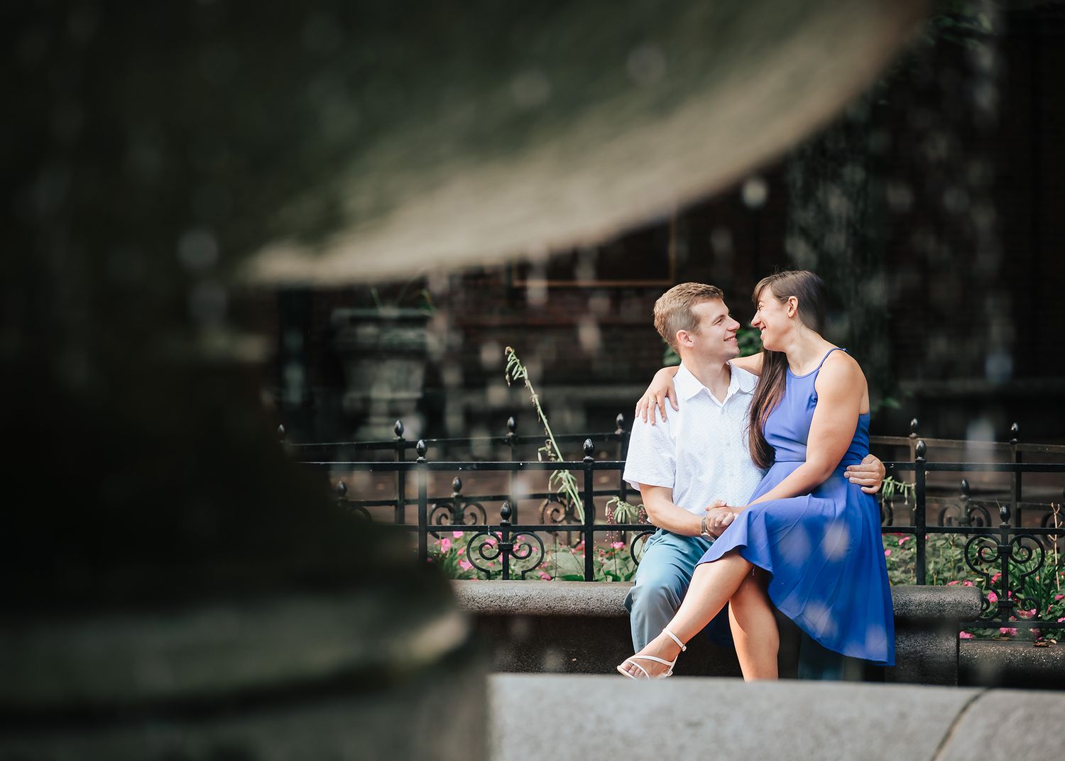 A newly engaged couple  embrace near the water fountain at Paul Revere Mall