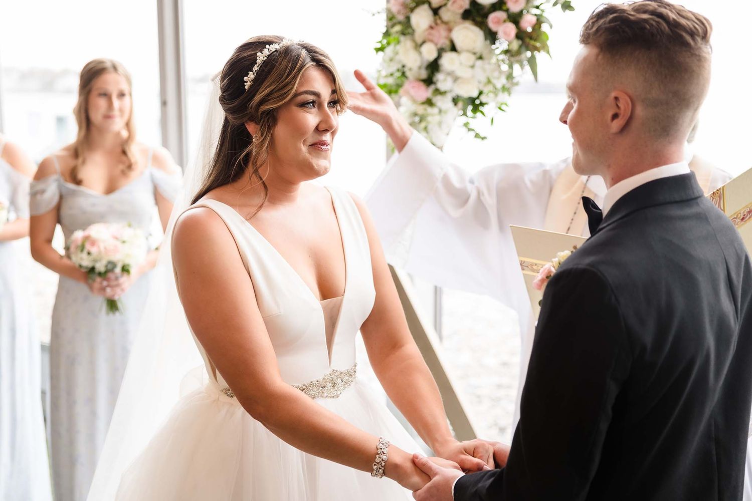 The bride is brought to tears as she holds hands with her groom during the wedding ceremony.