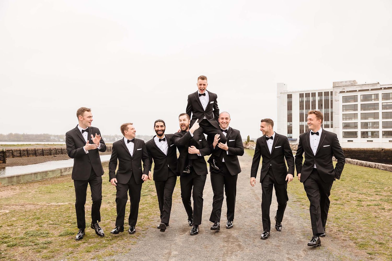 The groom is lifted up on the shoulder's of his groomsmen for a funny, candid moment on the morning of the wedding.