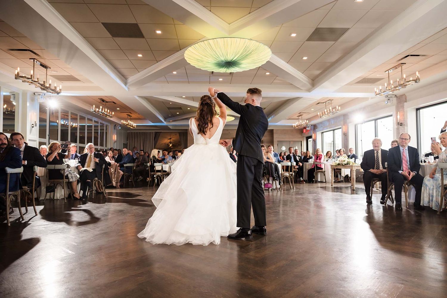 The groom gives his bride a dramatic twirl during their first dance at their wedding reception at the oceanview of Nahan