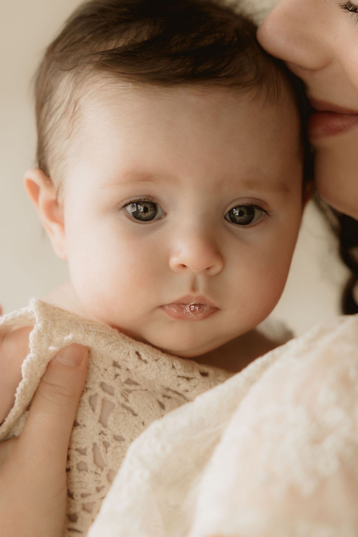 Close-up portrait series of a baby in a delicate white lace dress showing different expressions and angles.