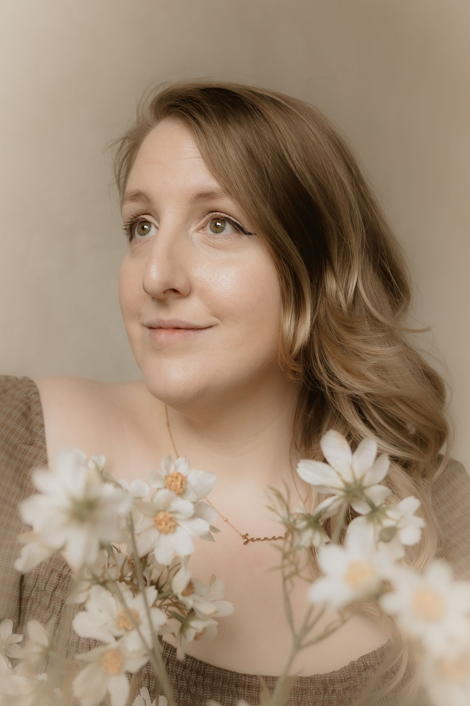 Soft portrait photograph with white daisies in foreground creating dreamy spring atmosphere in sepia tones.