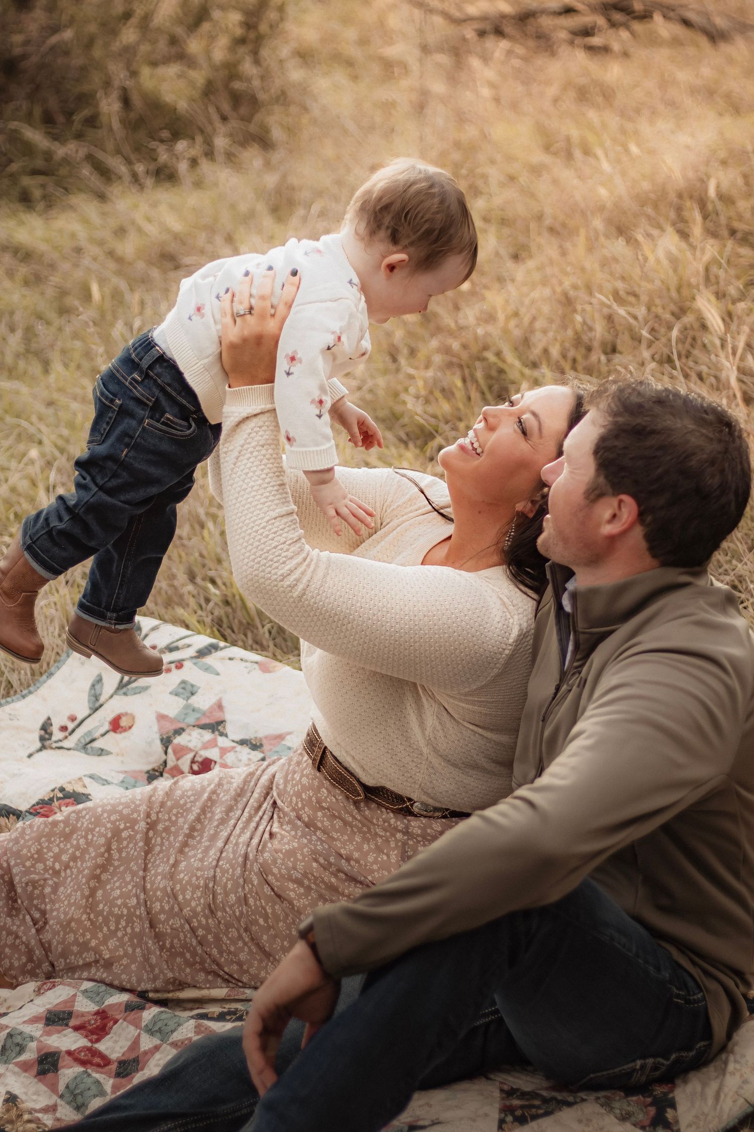 Young family sitting together in a field during an outdoor portrait session in York, Nebraska