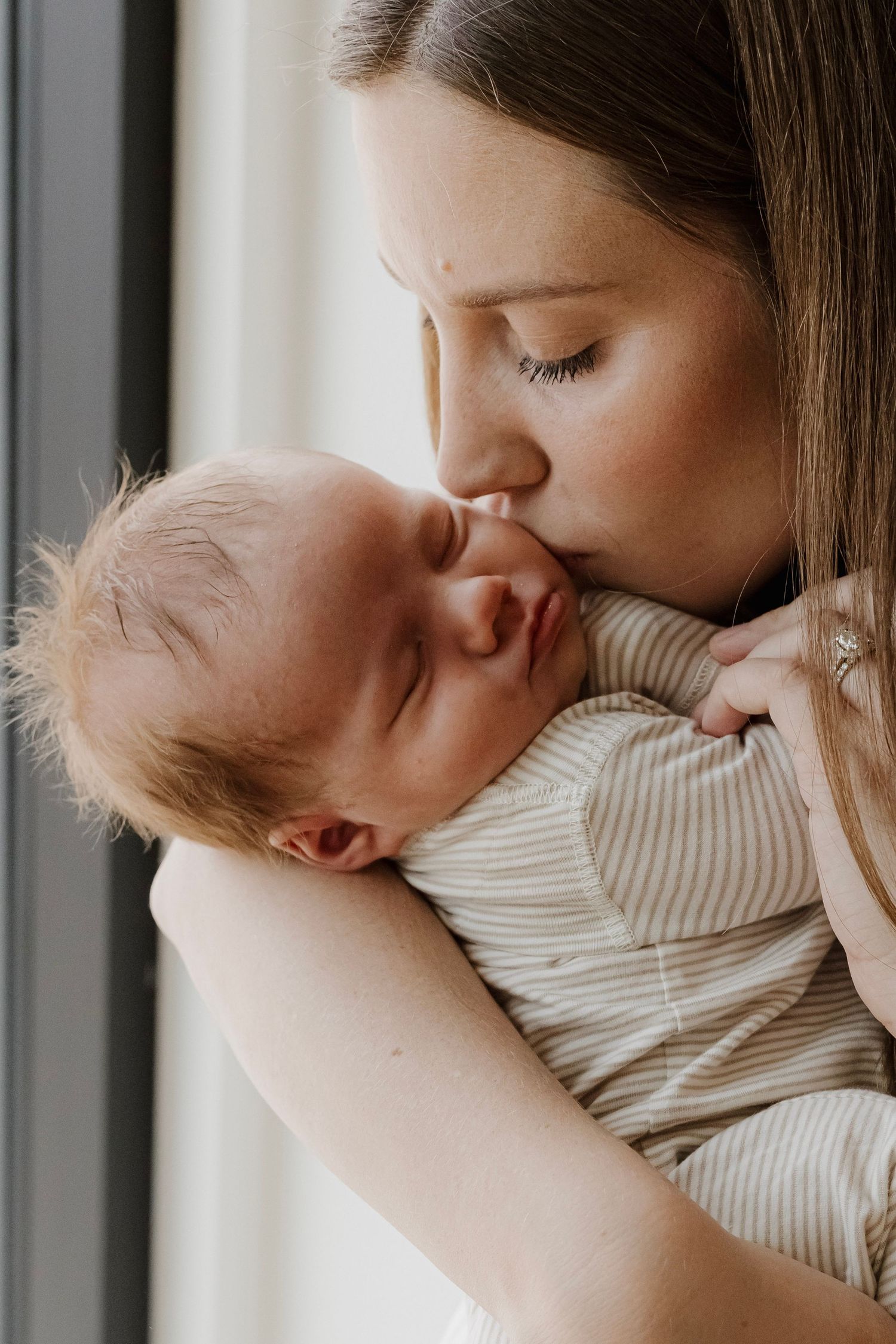 Mom kissing her baby during an indoor studio newborn lifestyle session in Hastings, Nebraska