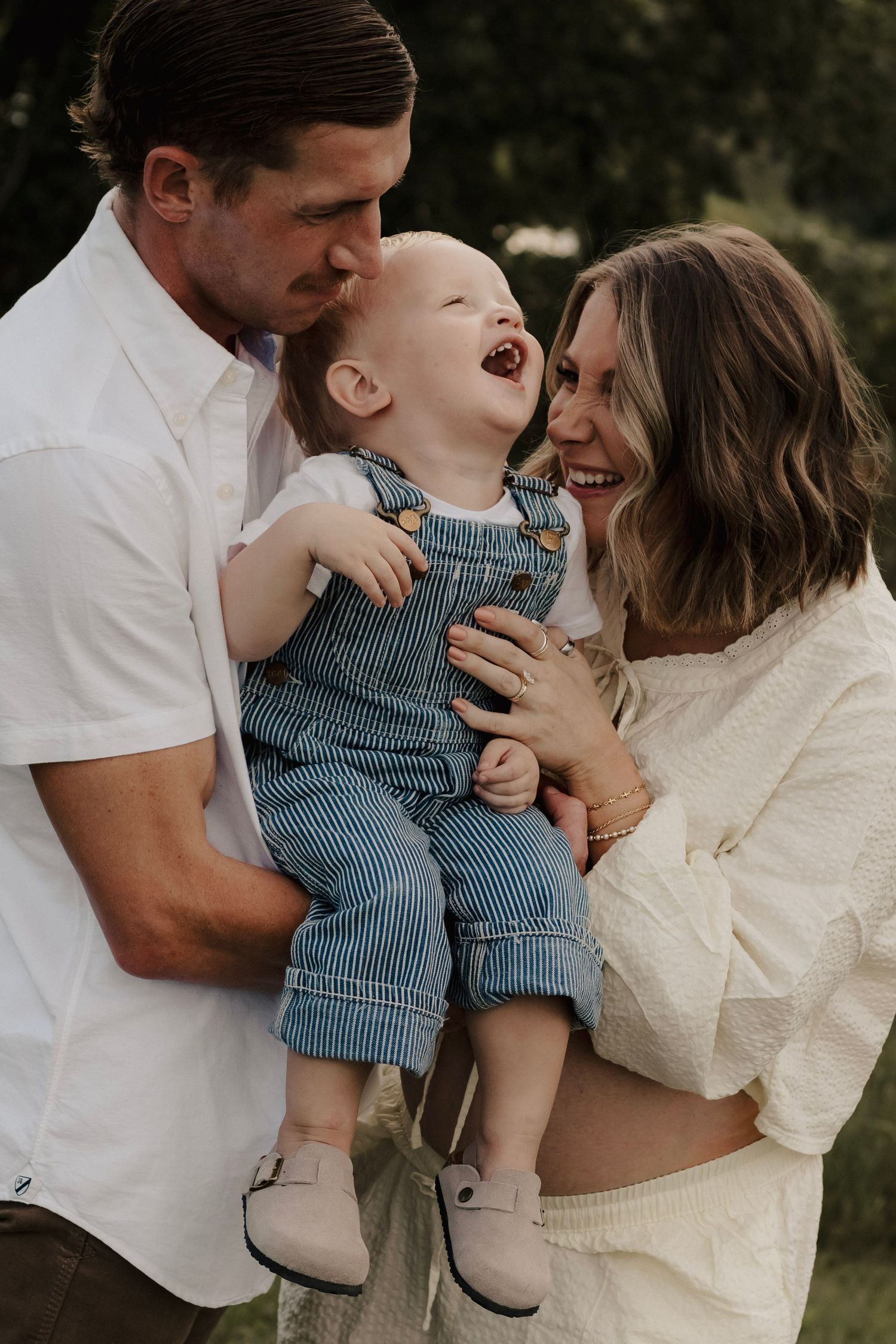 Mom and dad playing with toddler during outdoor family photos in Hastings, Nebraska