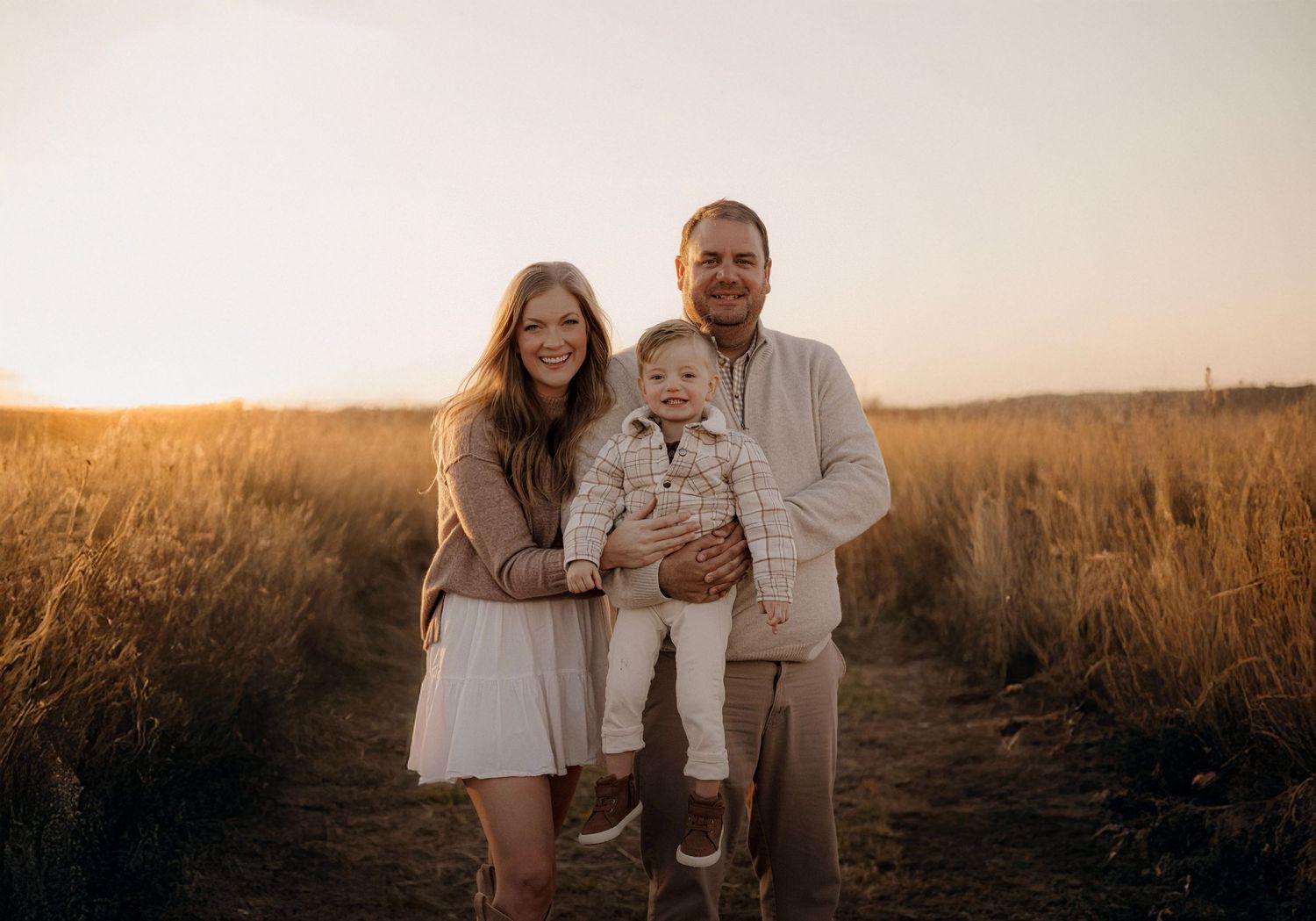 Family smiling together in a field during a golden hour family photo session