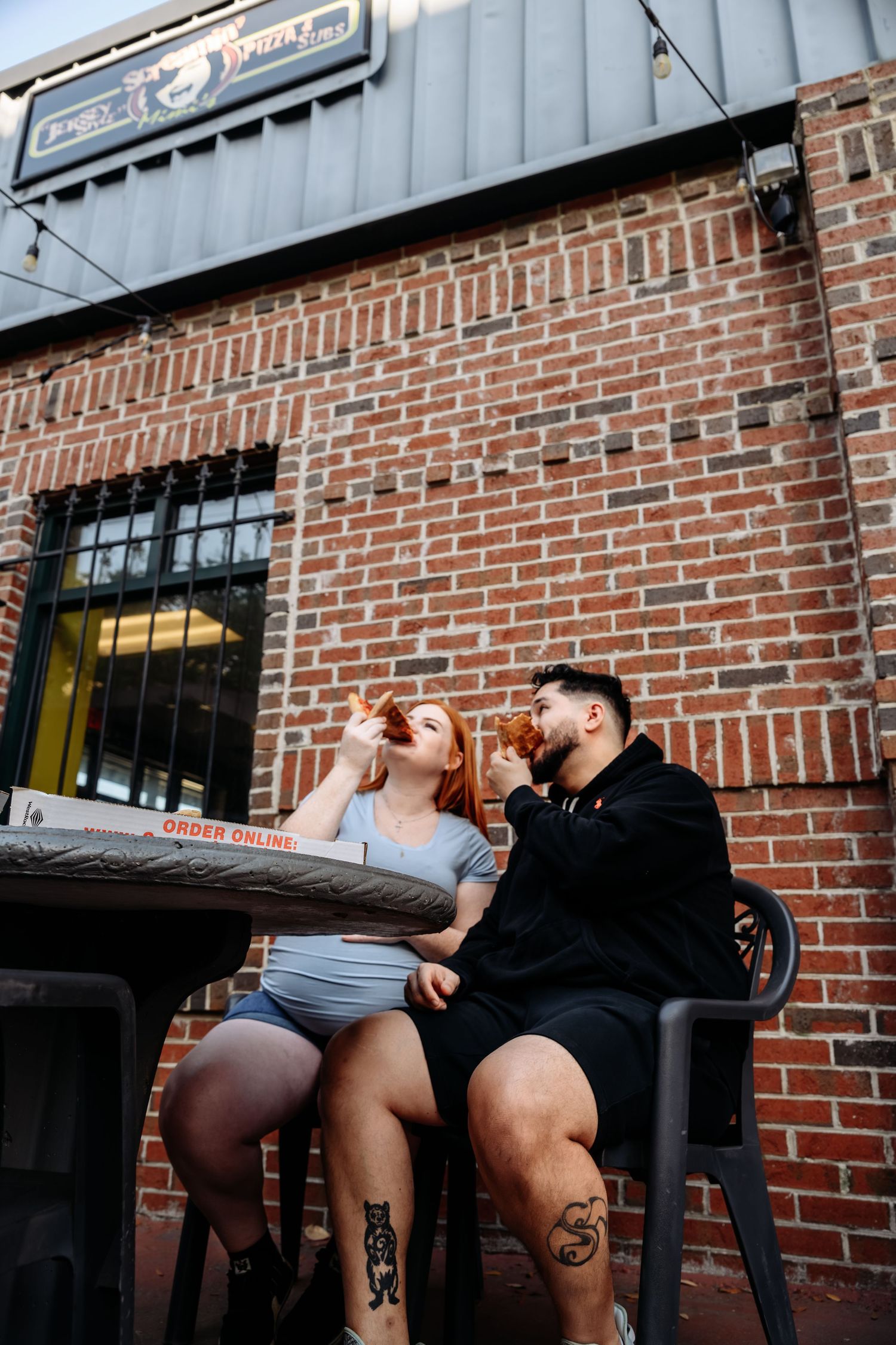 Couple sitting together at an outdoor brick restaurant patio table sharing drinks on a warm day.