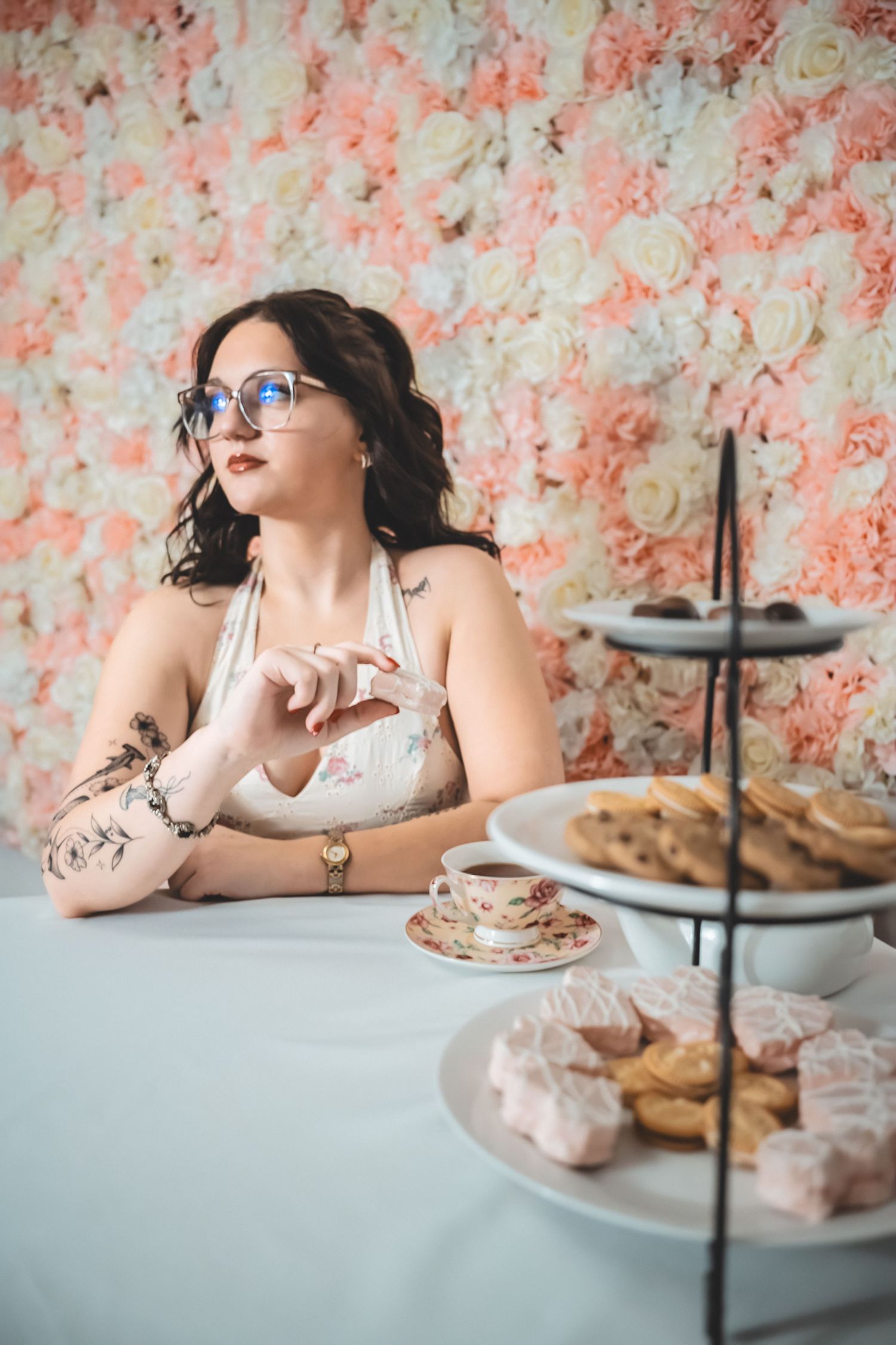 A vintage-inspired tea party setup with a tiered dessert stand and floral wallpaper backdrop creates an elegant atmosphere.