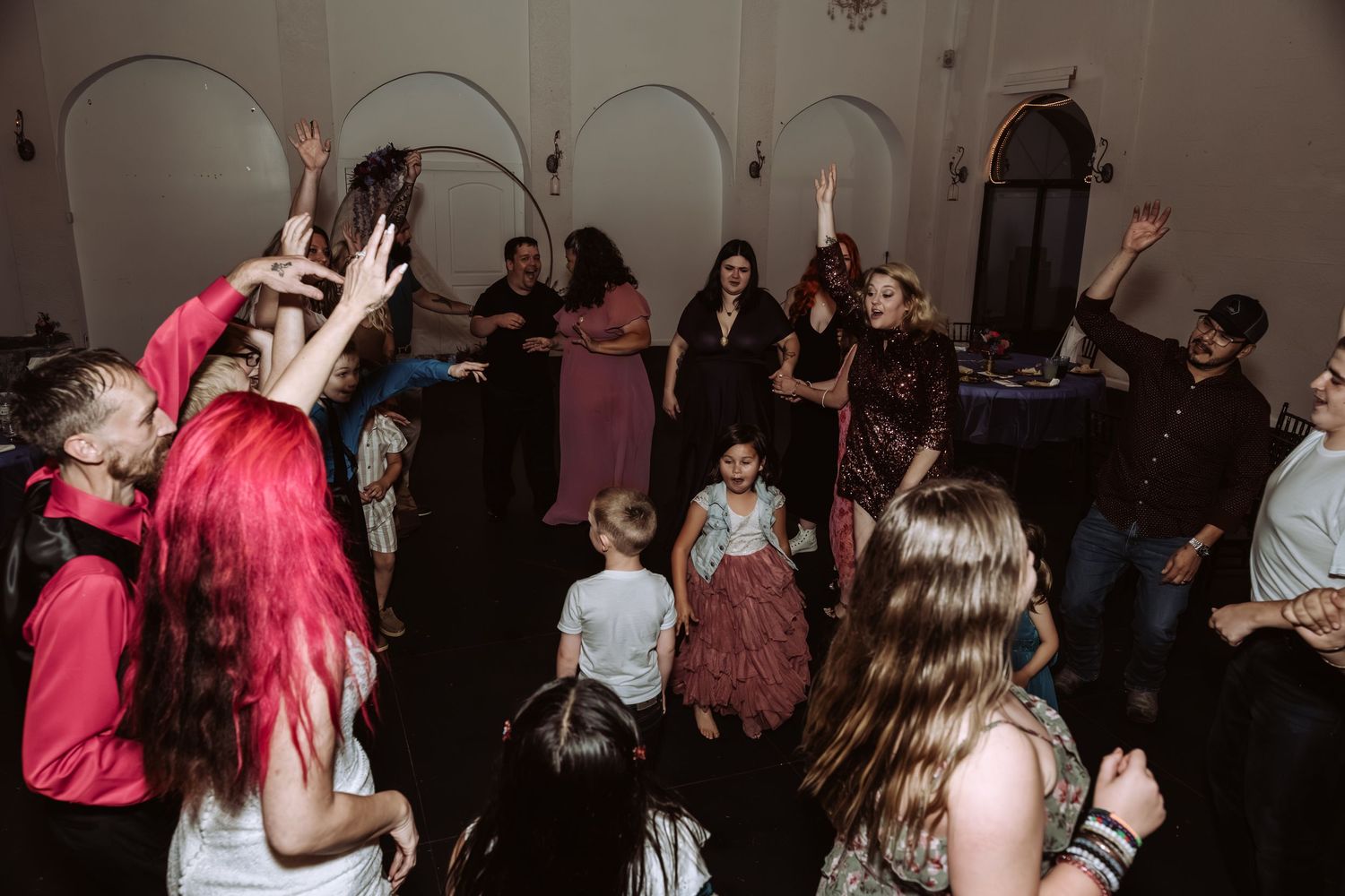 Wedding guests dancing and celebrating on the dance floor during a lively wedding reception party.