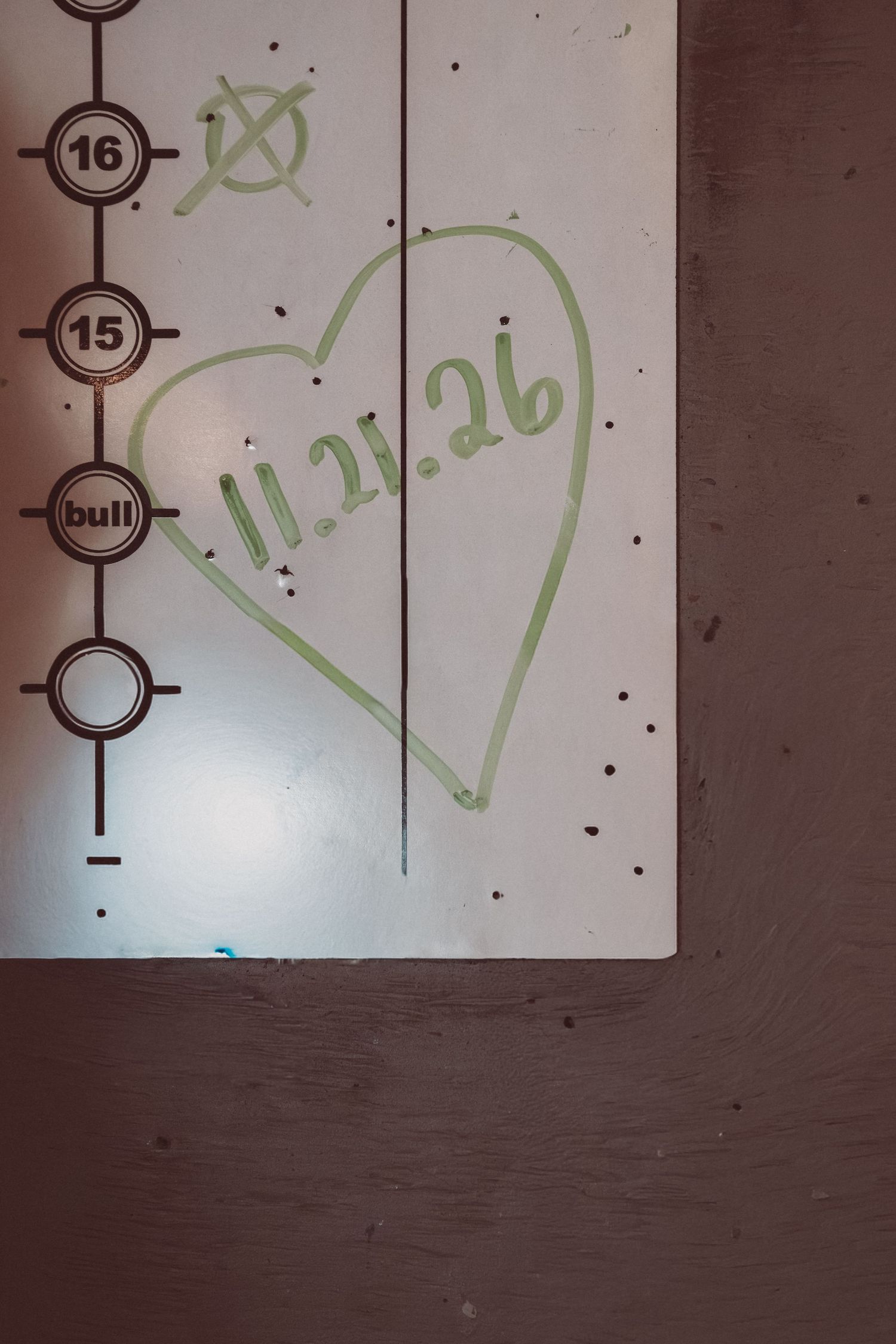 A dartboard scoreboard with a hand-drawn heart and the date 11.21.26 written in green marker.