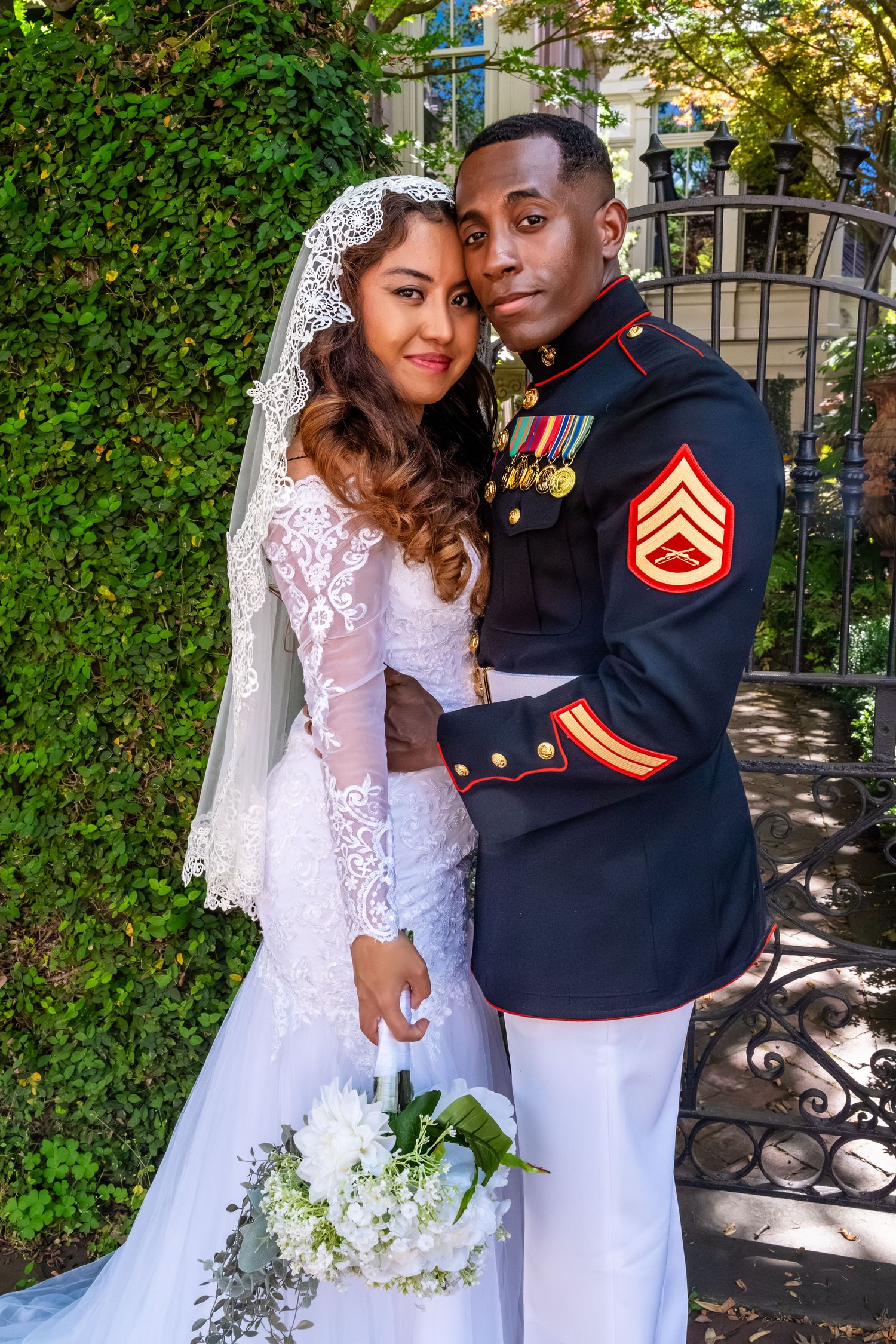 Couple poses together on wedding day, groom wearing decorated Marine Corps dress uniform with medals.