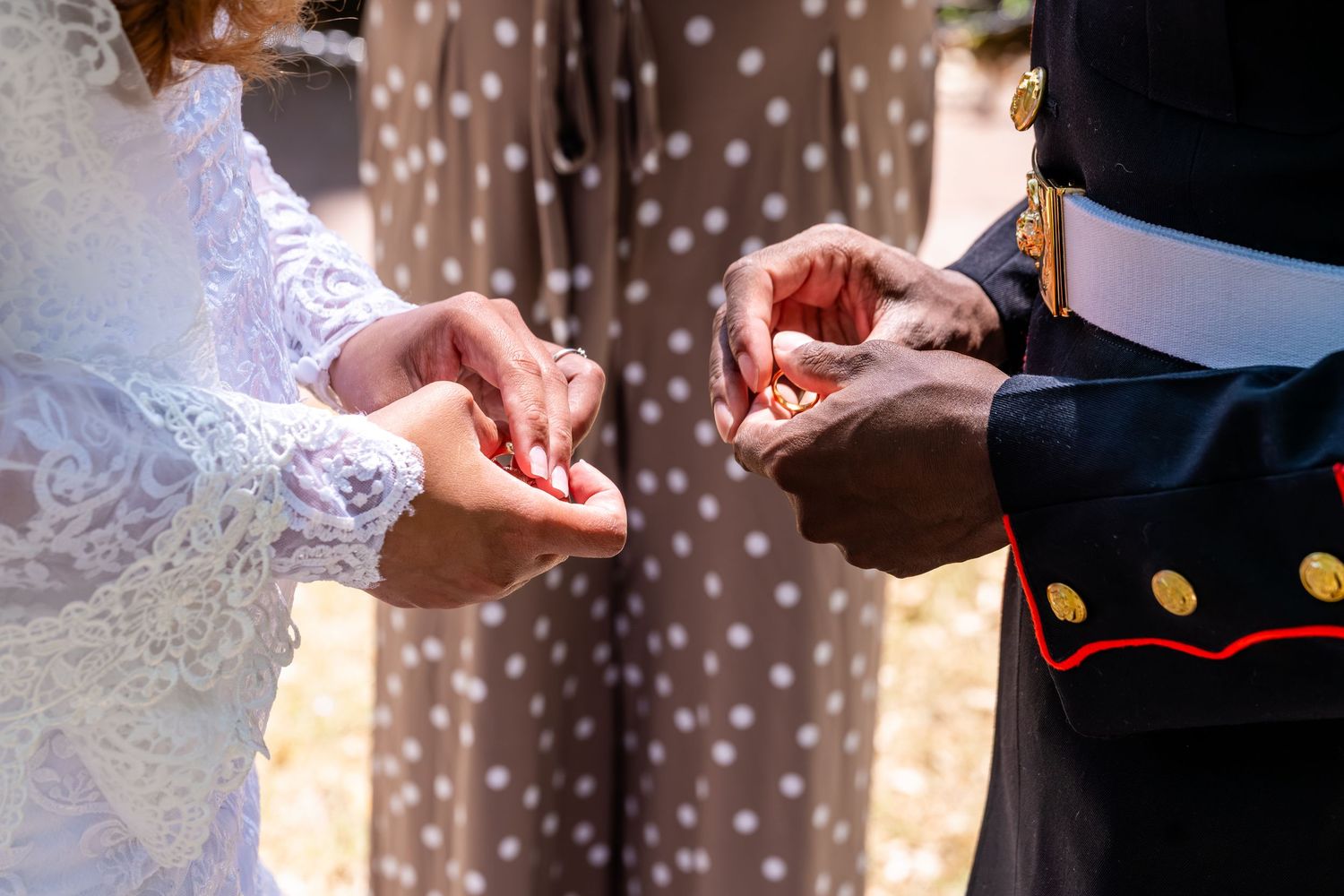 Close-up of bride and Marine groom exchanging wedding rings during their outdoor wedding ceremony.