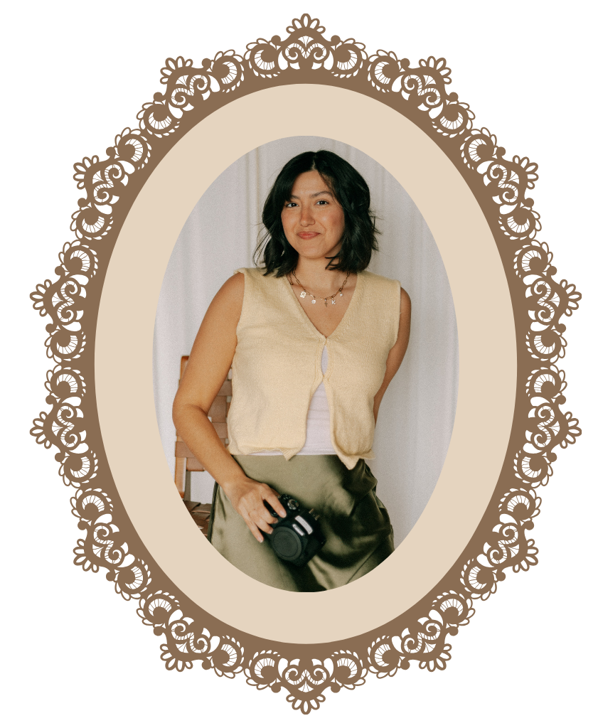 A woman with dark hair holding a camera, framed in an ornate vintage oval brown lace border.