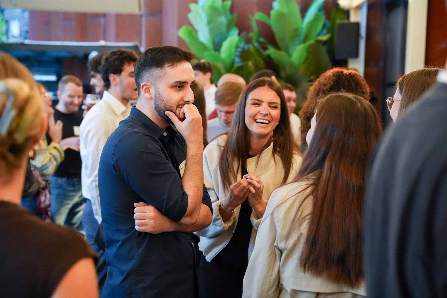 Group of young professionals socializing and laughing at a casual networking event.