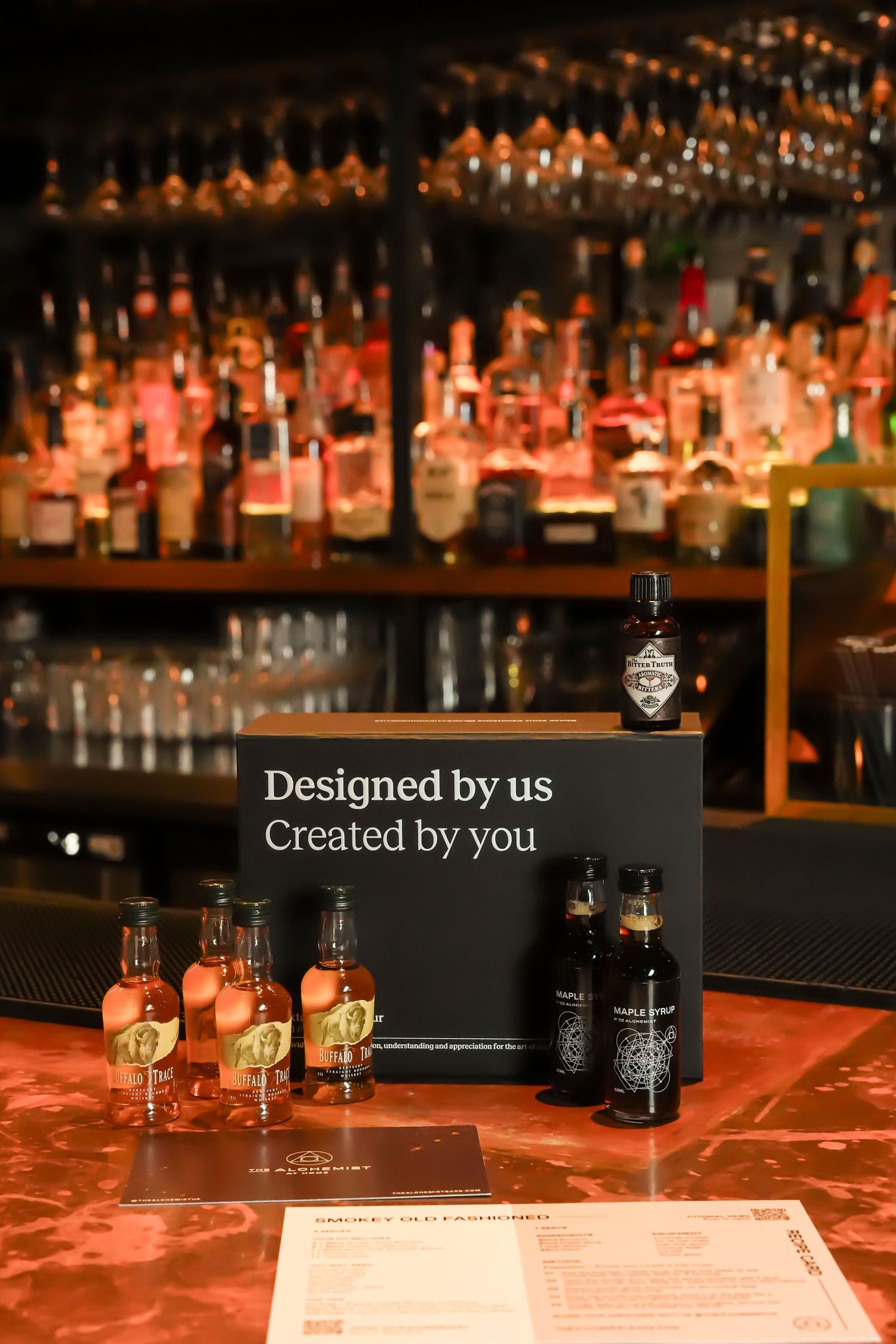 Bar display featuring cocktail kit with bottles, glasses and designed by us branding sign.