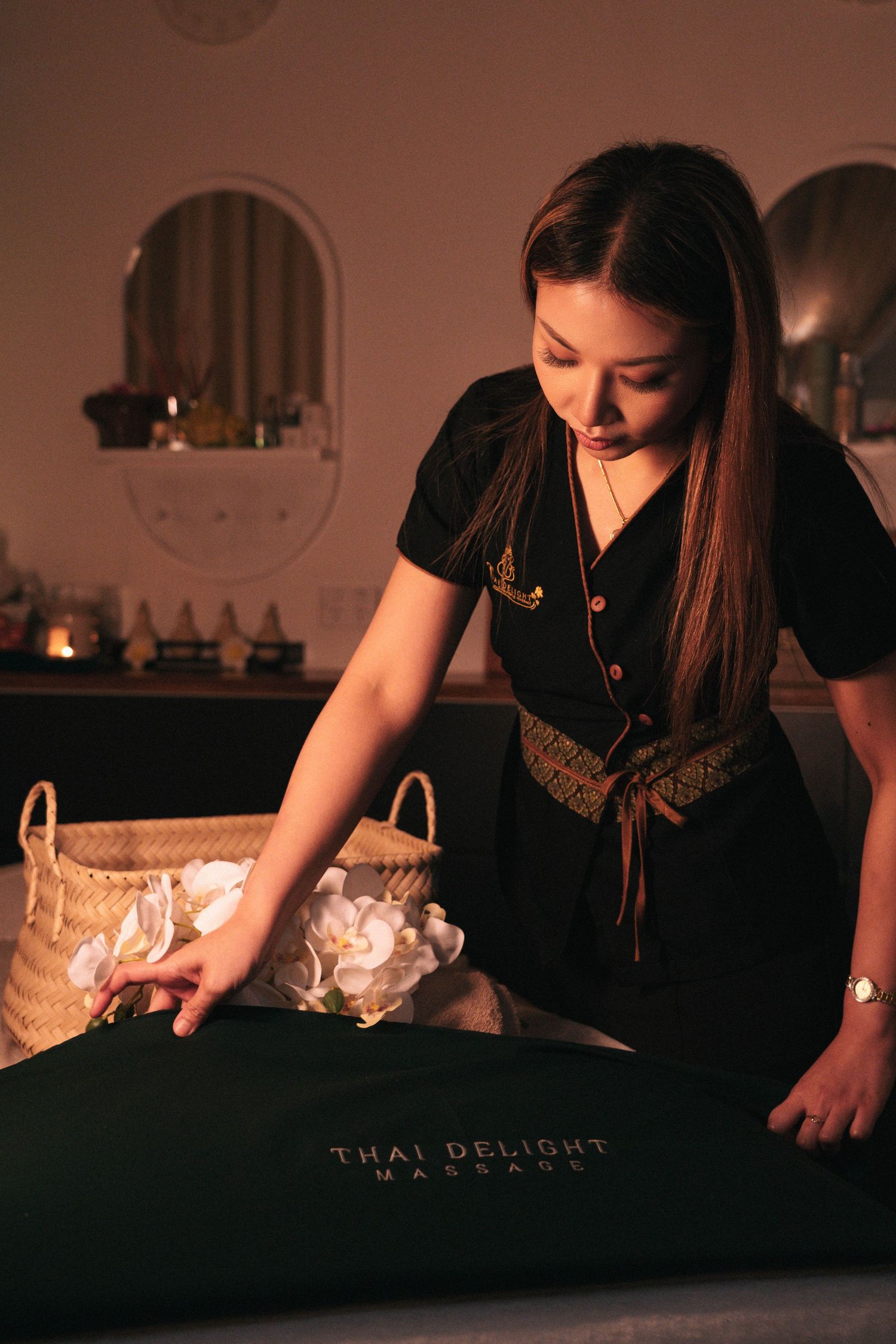 Storytelling brand imagery in branding photography sessions captures a massage therapist in black attire preparing a treatment table.