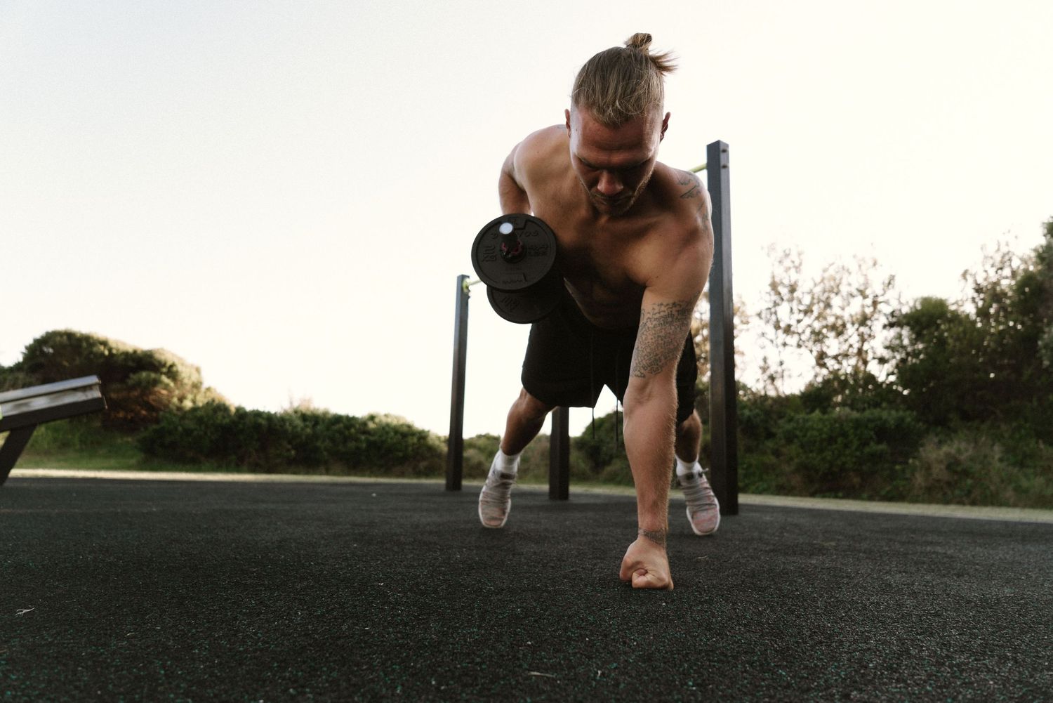 Branding Photography Sessions capturing a shirtless wellness coach performing a dynamic kettlebell exercise on an outdoor track