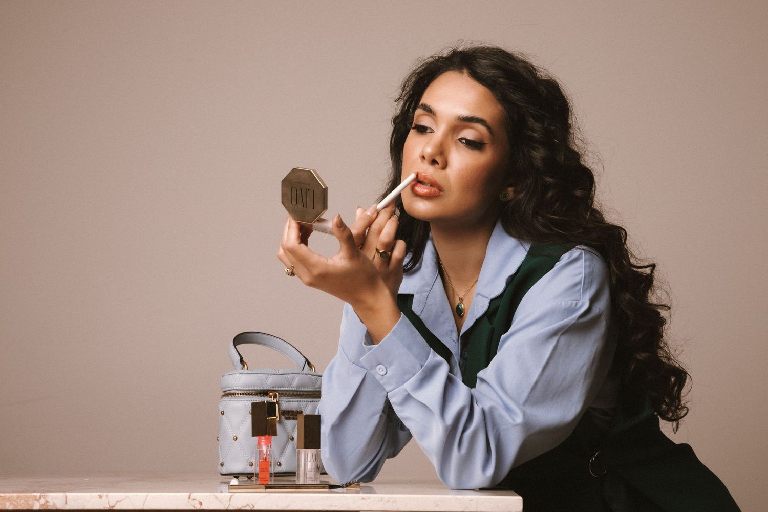 Professional photo of a makeup artist applying makeup at a table with a jar and mirror, showcasing branding photography sessions