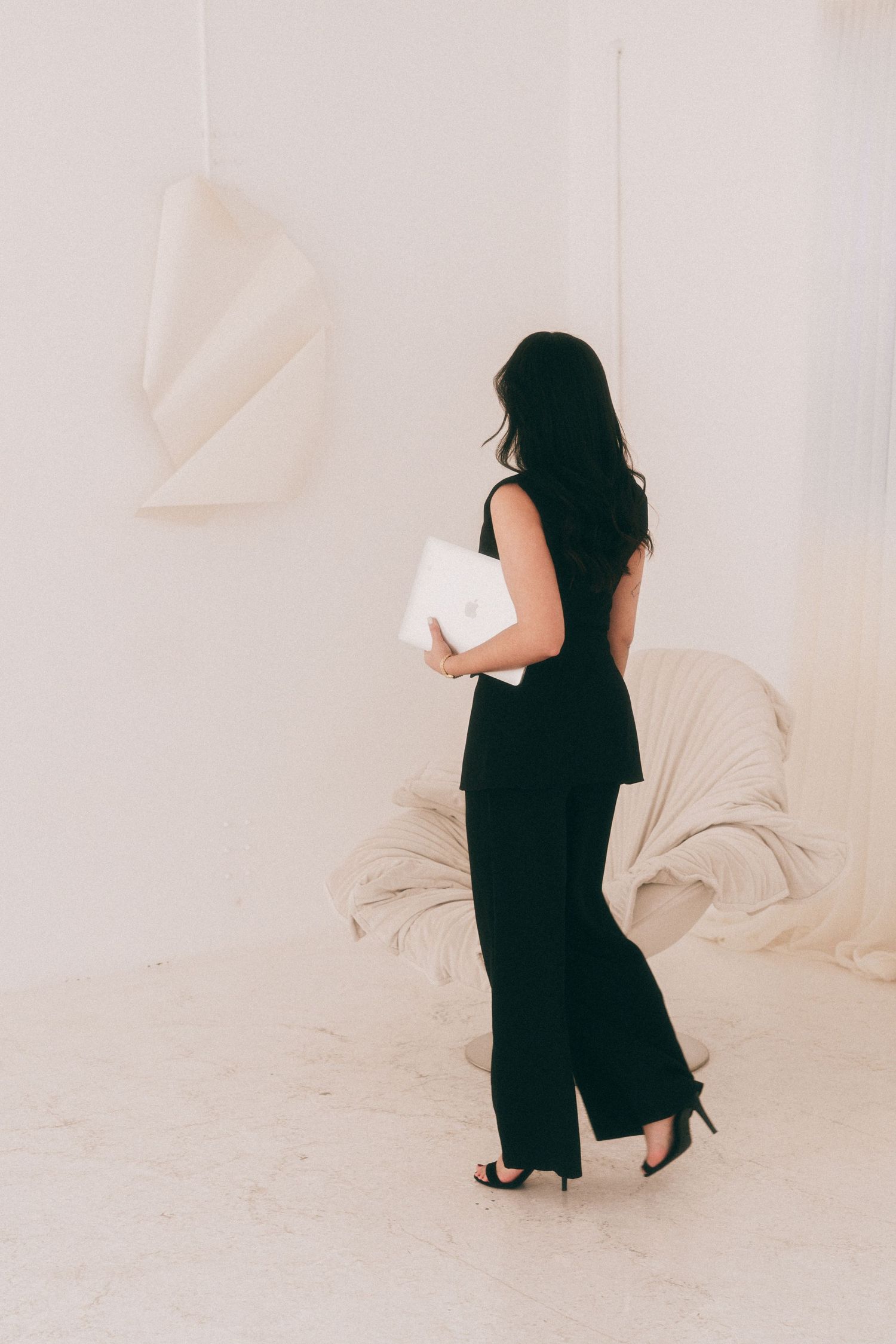 Branding Photography Sessions capture a sophisticated entrepreneur in a fitted black pantsuit and heels walking across a minimalist.