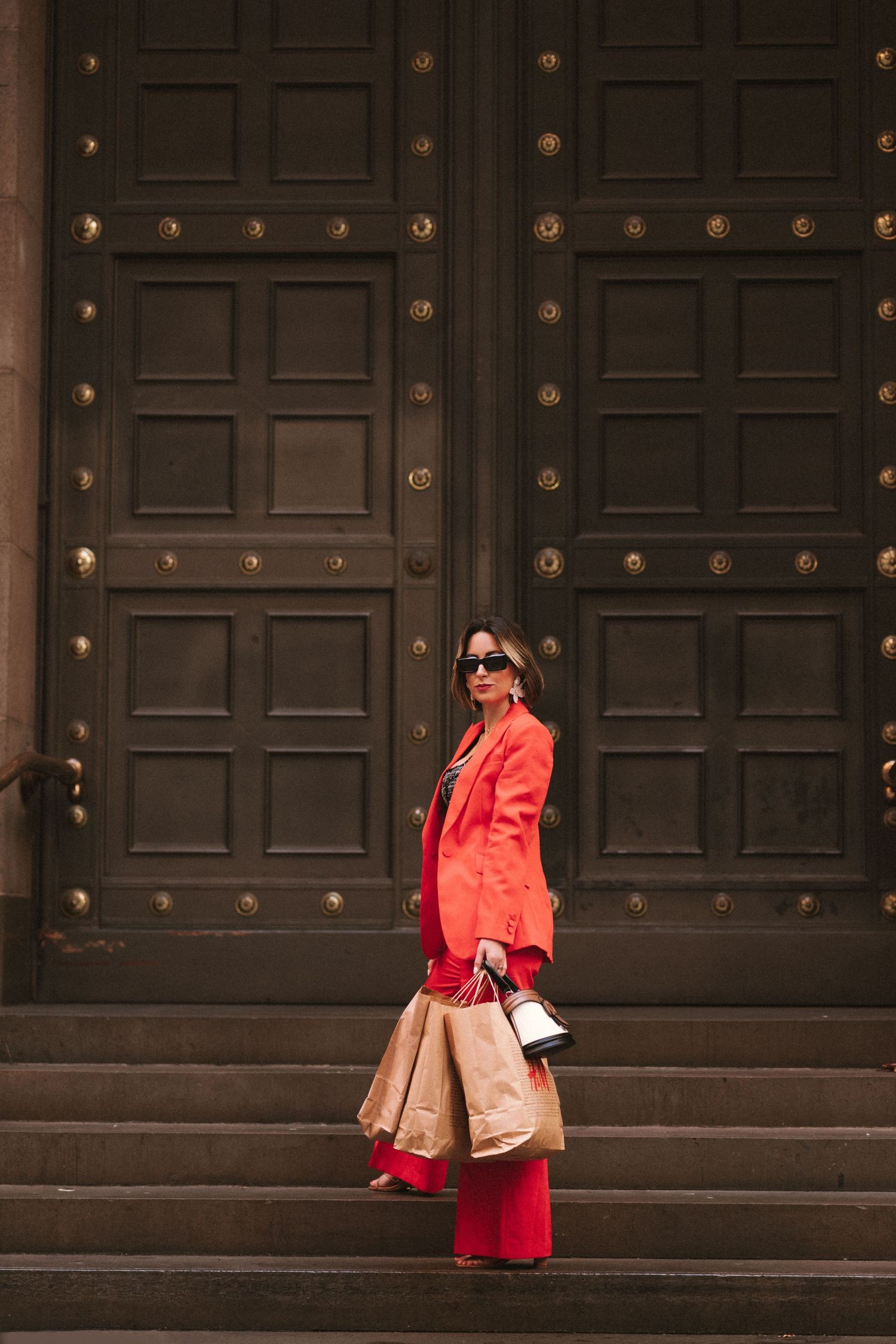 Branding Photography Sessions capture a stylist in a bright red monochrome outfit with shopping bags, standing on steps.