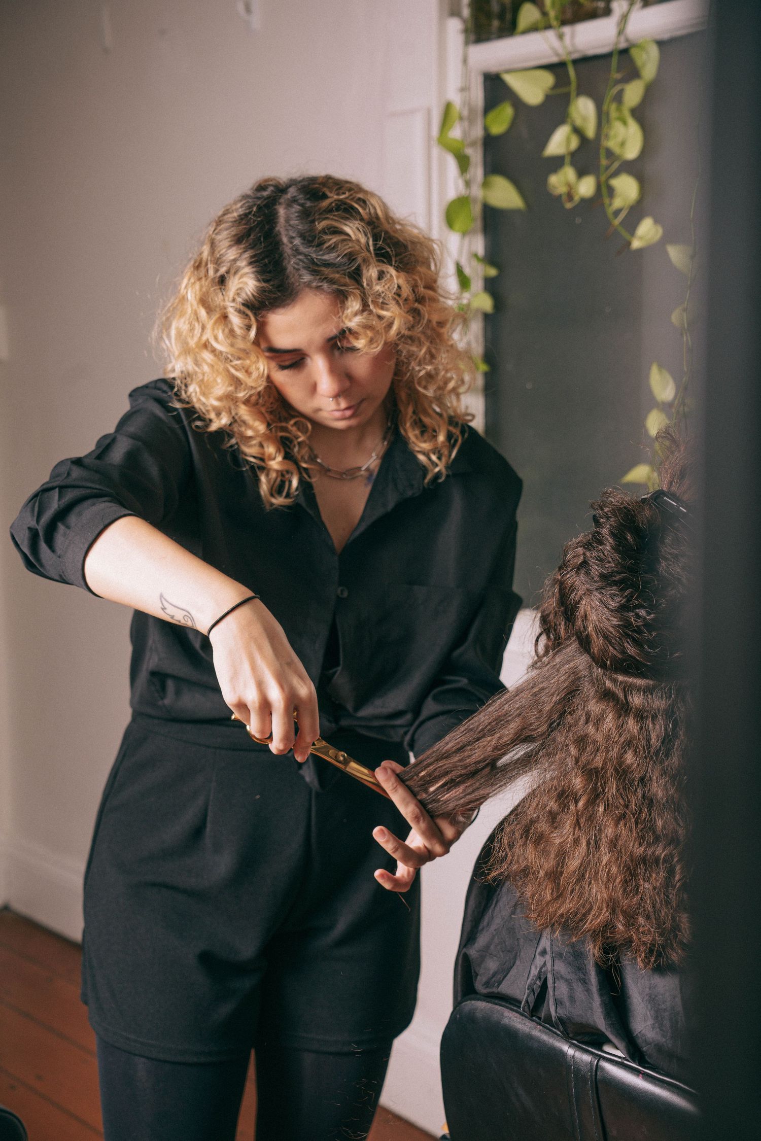 Sydney branding photographer captures a professional hairdresser in black attire trimming a client’s long brown hair