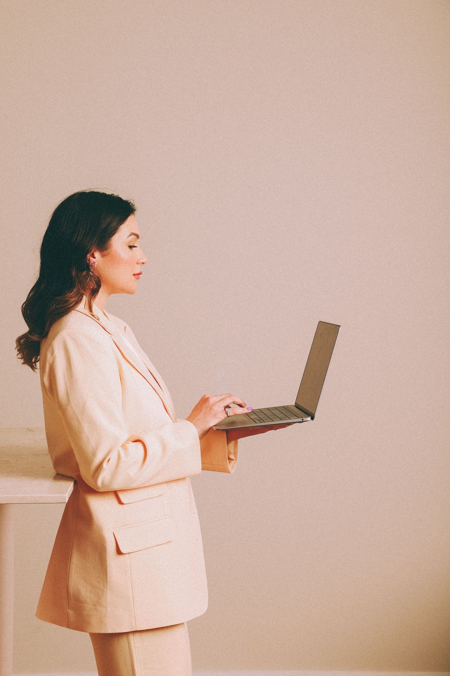Branding Photography Sessions capture a professional in a light beige pantsuit working on a laptop, showcasing high-converting brand shoot