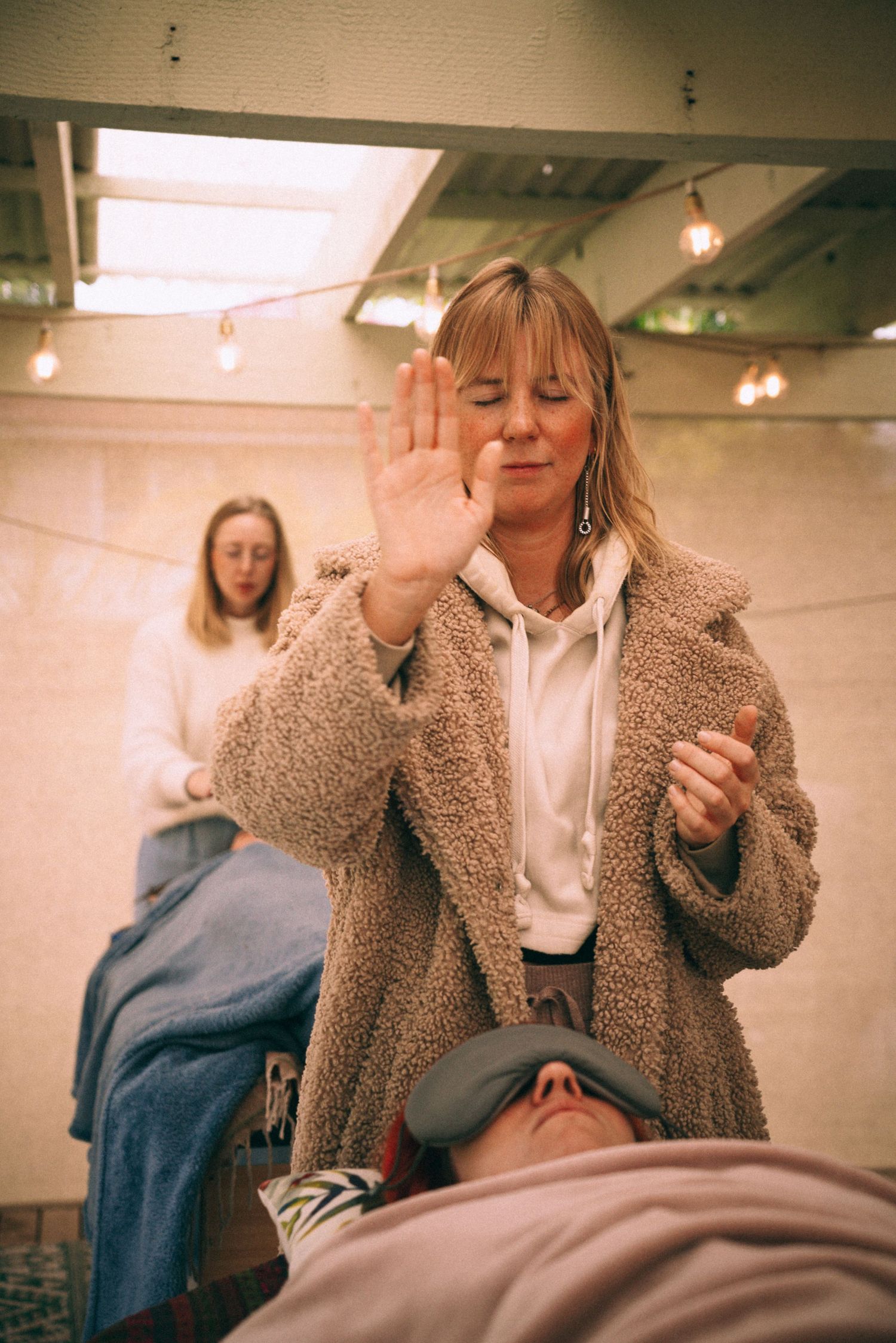 Branding Photography Sessions for a wellness coach capture an entrepreneur raising their hand during an alternative healing session.