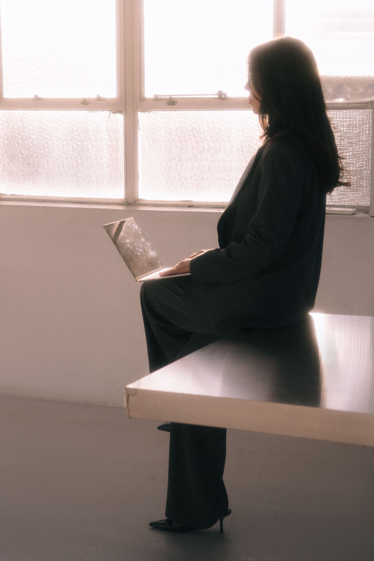 Branding Photography Sessions capture an entrepreneur in a storytelling brand imagery, silhouetted by a window while reading a book.