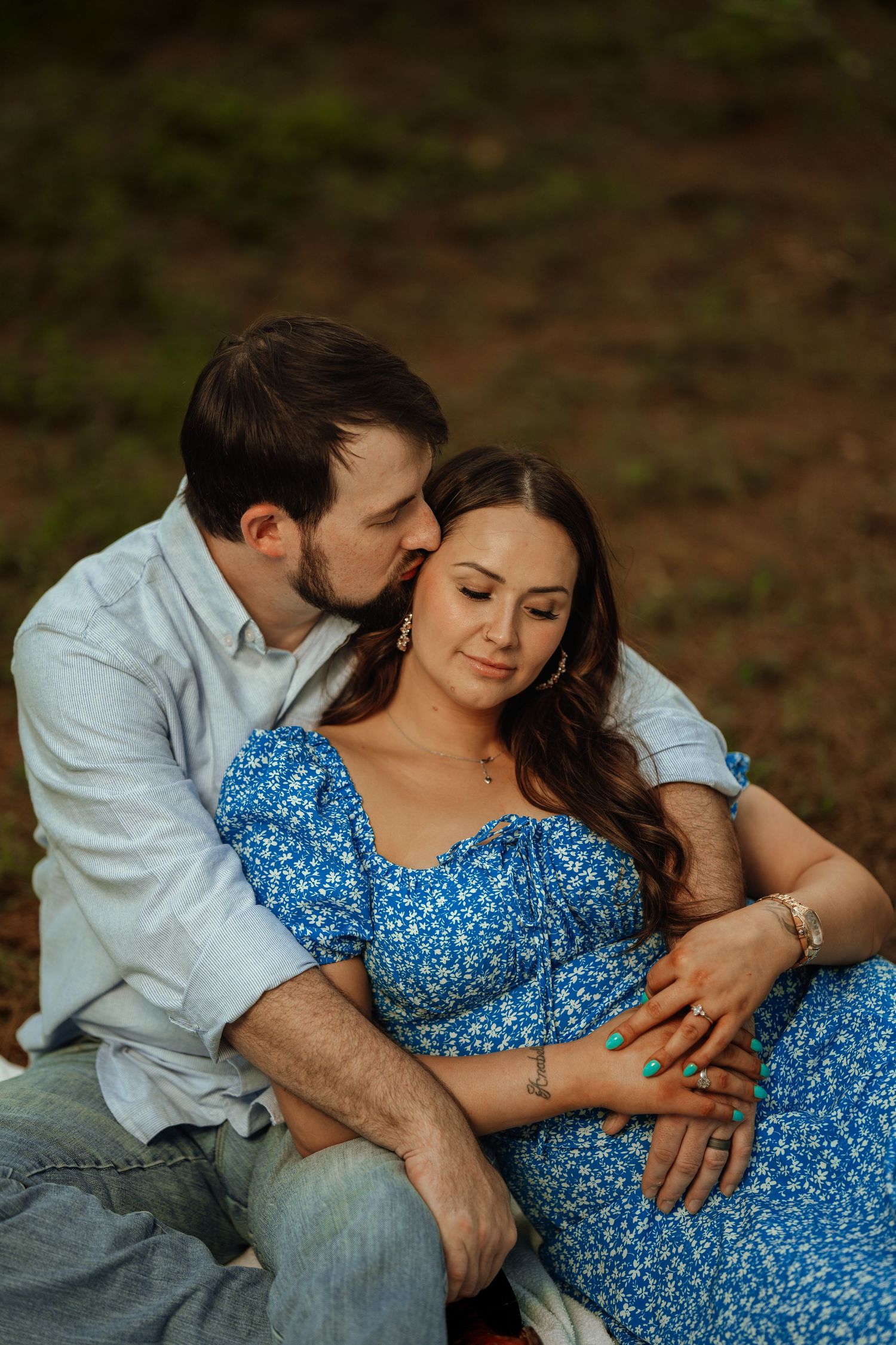 A couple sharing an intimate moment while sitting outdoors in warm lighting.