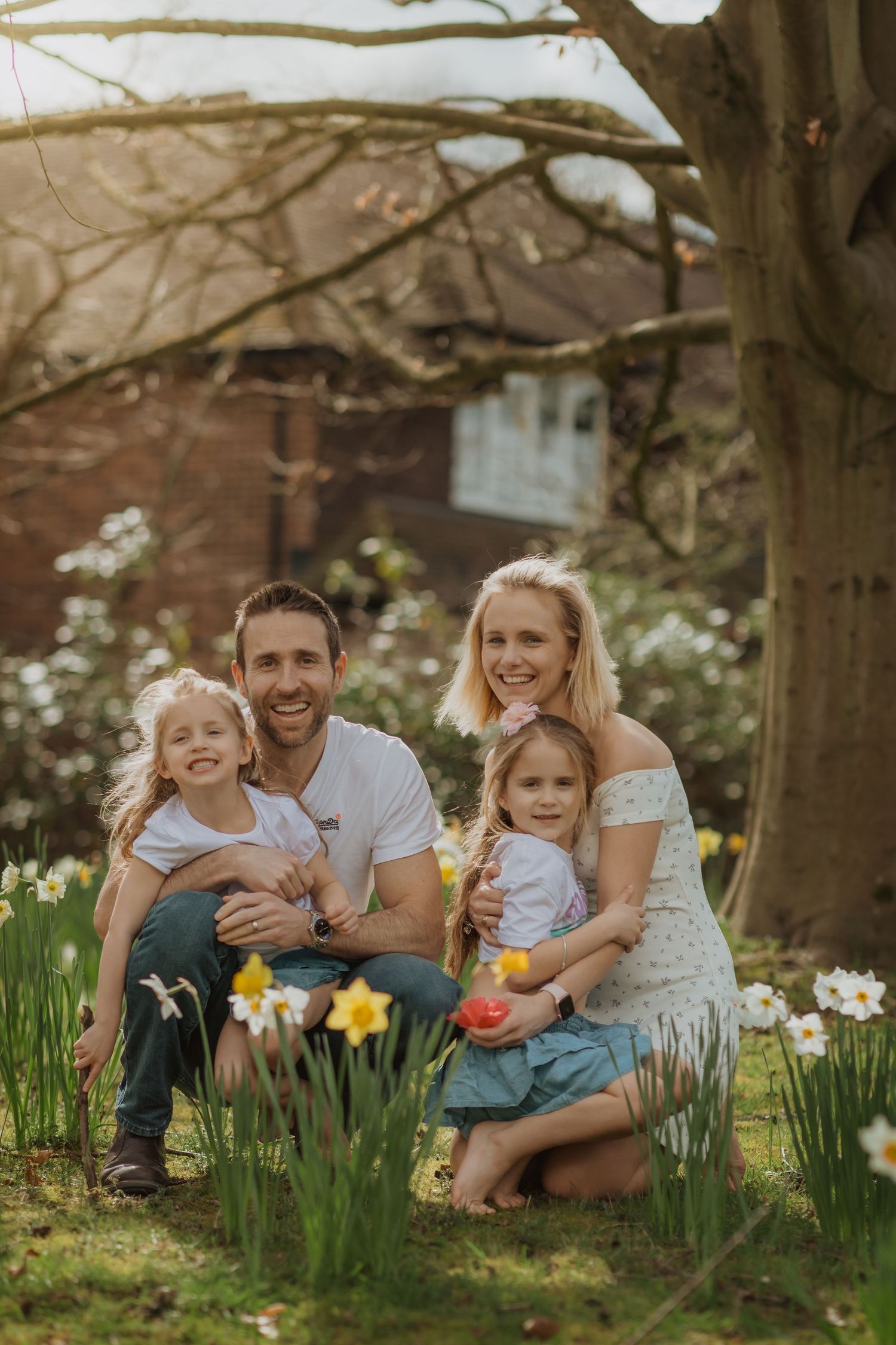Happy family sitting among spring daffodils in a garden setting.