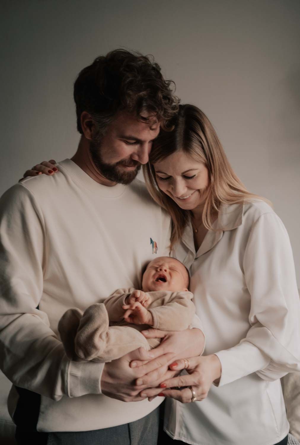 ein Paar in einem Baby Fotoshooting, die ihren neugeborenen Baby tragen bei den Kunden zuhause in Köln, NRW.
