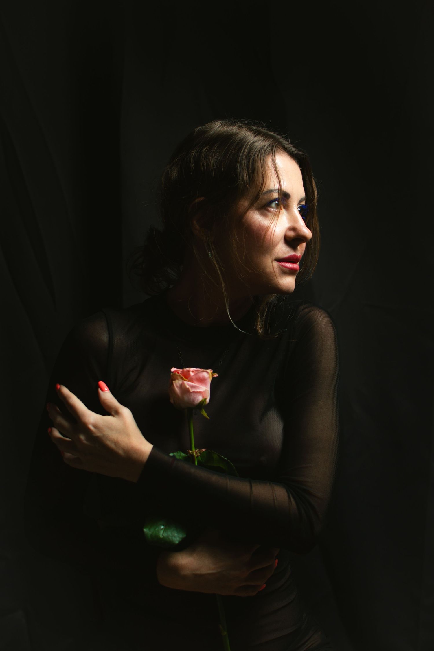Sensual Portrait von einem Model die eine Rose trage und guckt in  die Seite in einem Fotoshooting indoor in Homestudio.