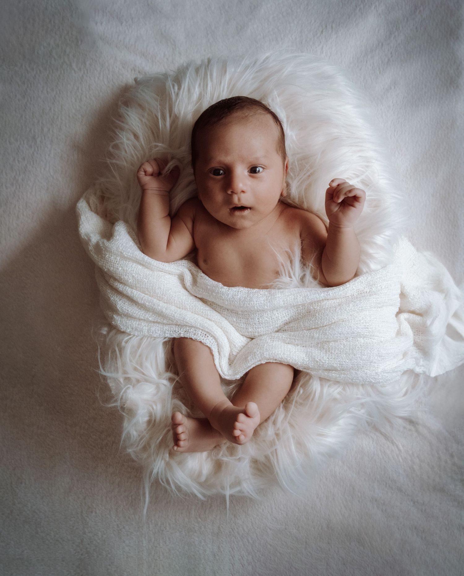 Baby in Bett in einem Baby Fotoshooting bei den Eltern zuhause.