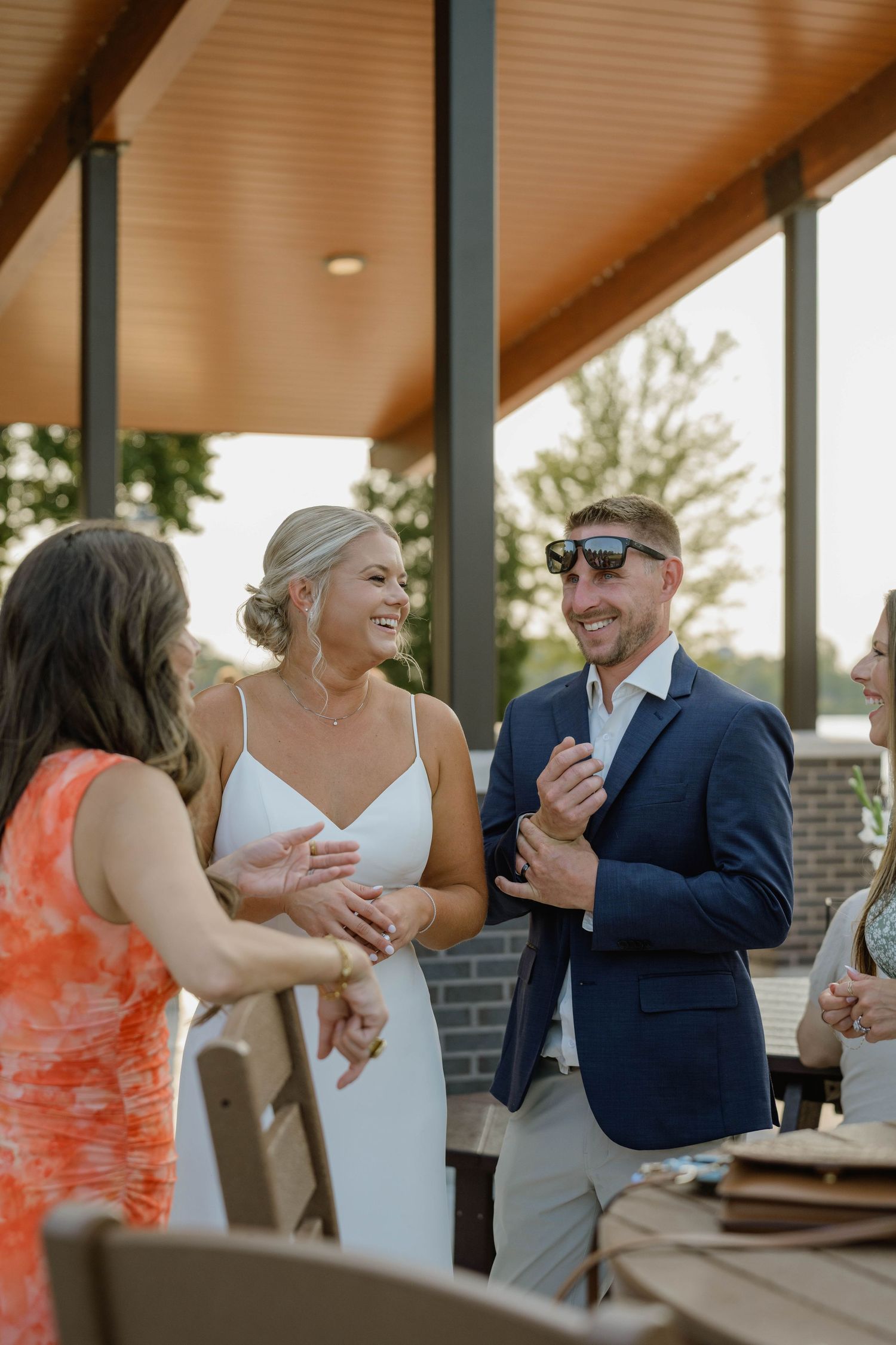 Bride and groom laughing and socializing with guests at their outdoor wedding reception.