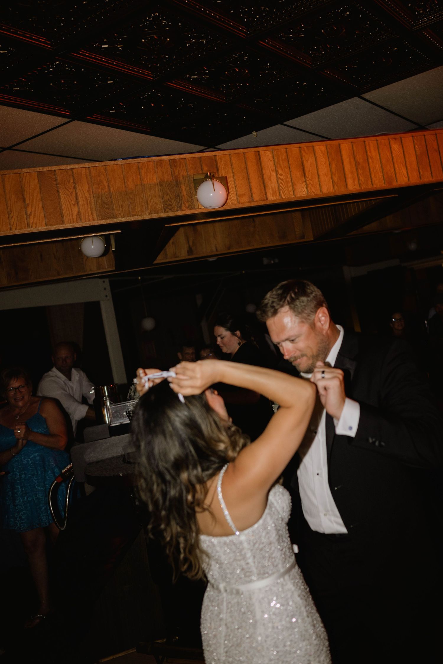 Bride and groom sharing first dance in dimly lit wedding reception venue.