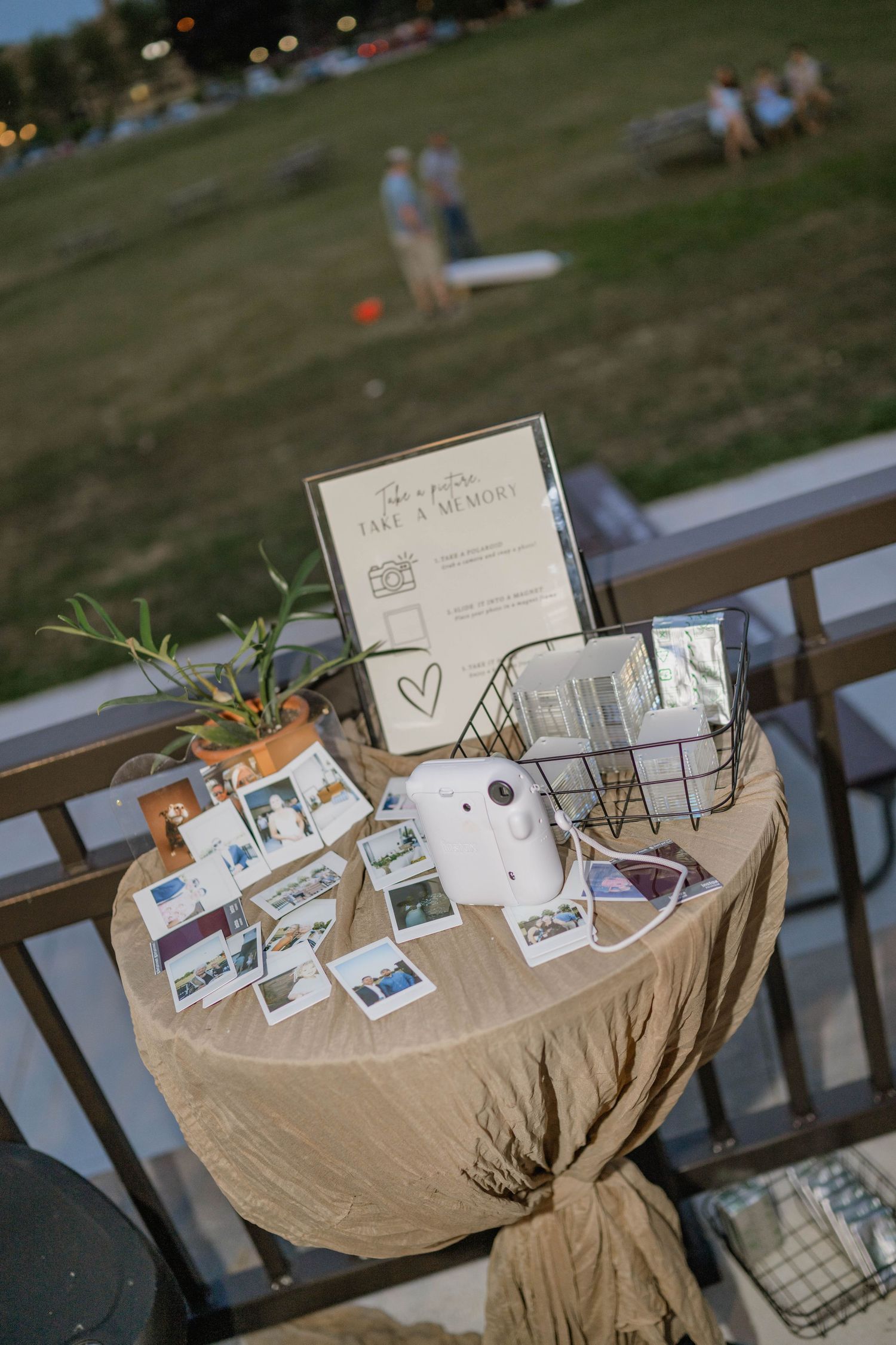 Rustic wedding photo booth table with Instax camera, polaroid photos, and take a memory sign.