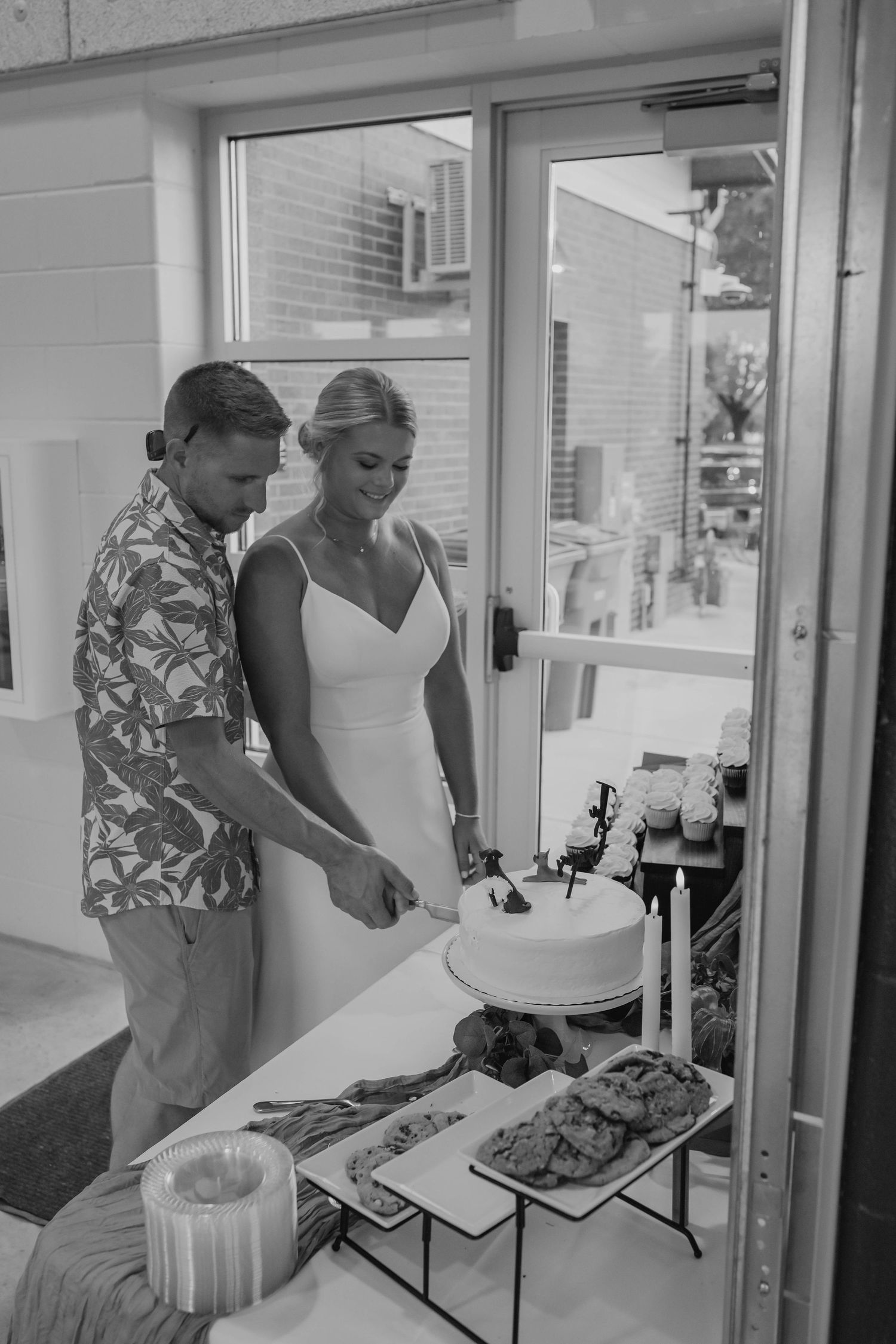 Bride and groom cutting their wedding cake together in black and white photo.