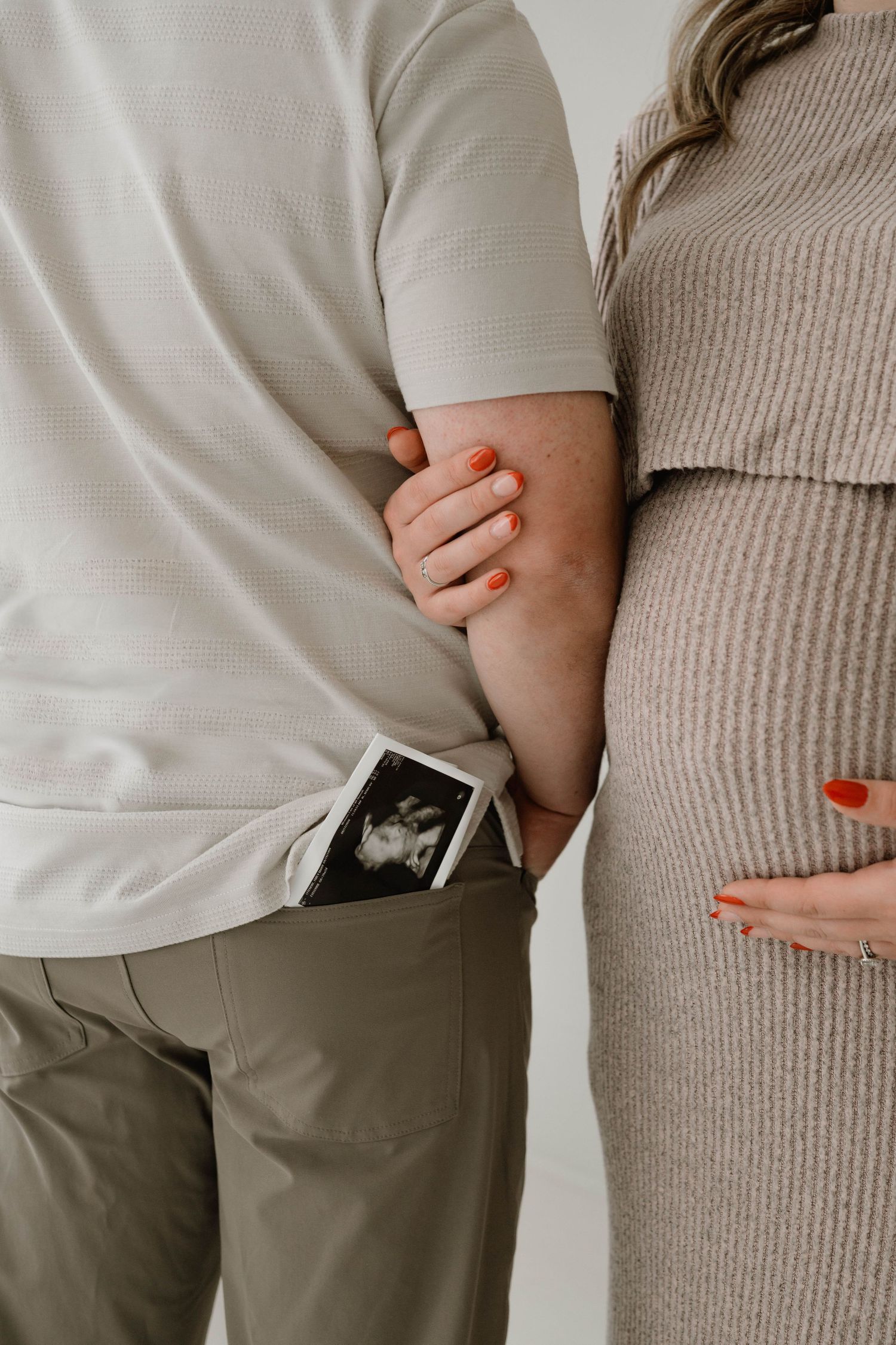 Close-up of expecting couple holding hands with ultrasound photos tucked in mans pocket.