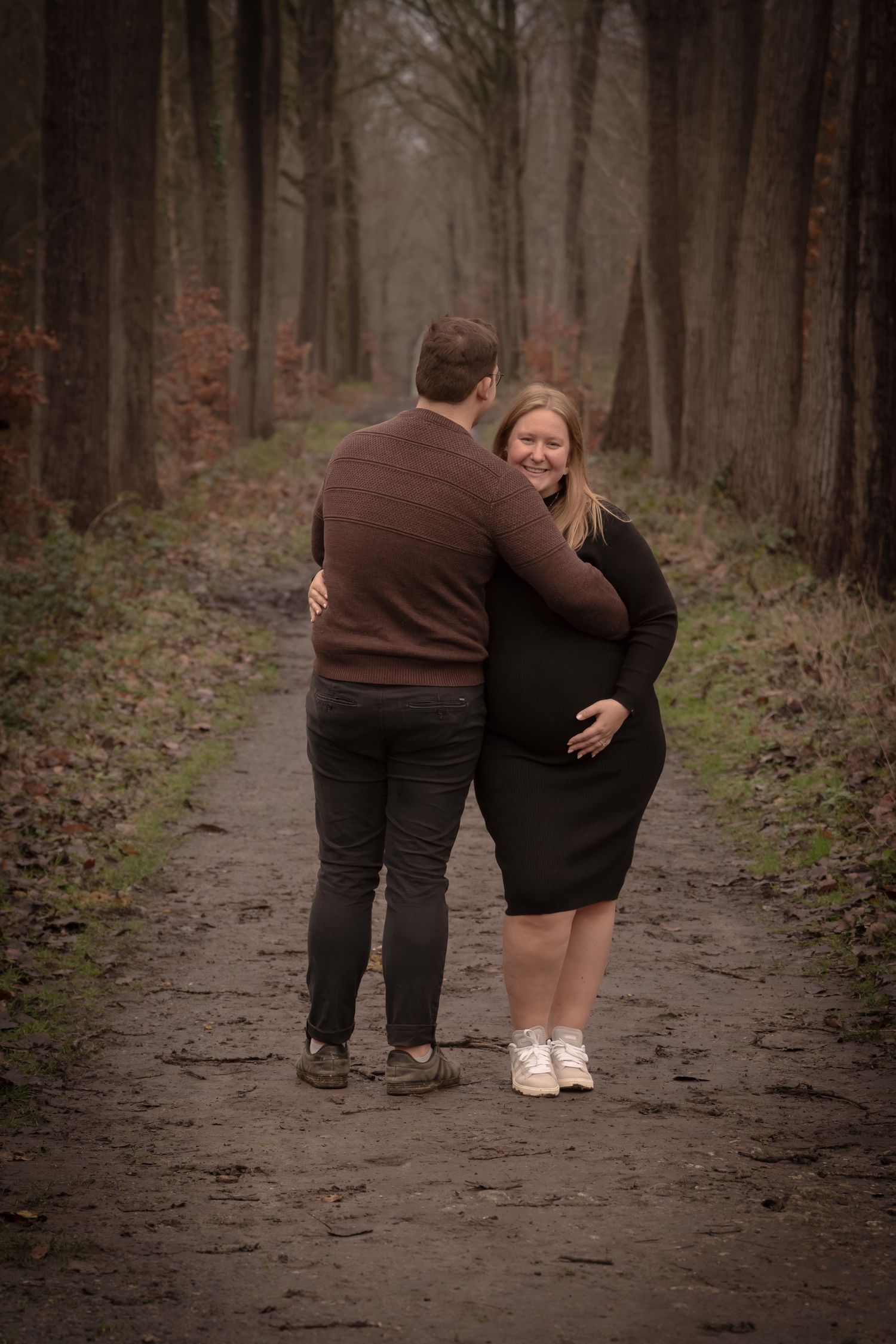 A couple walks together down a wooded path in autumn, captured in a series of candid moments.
