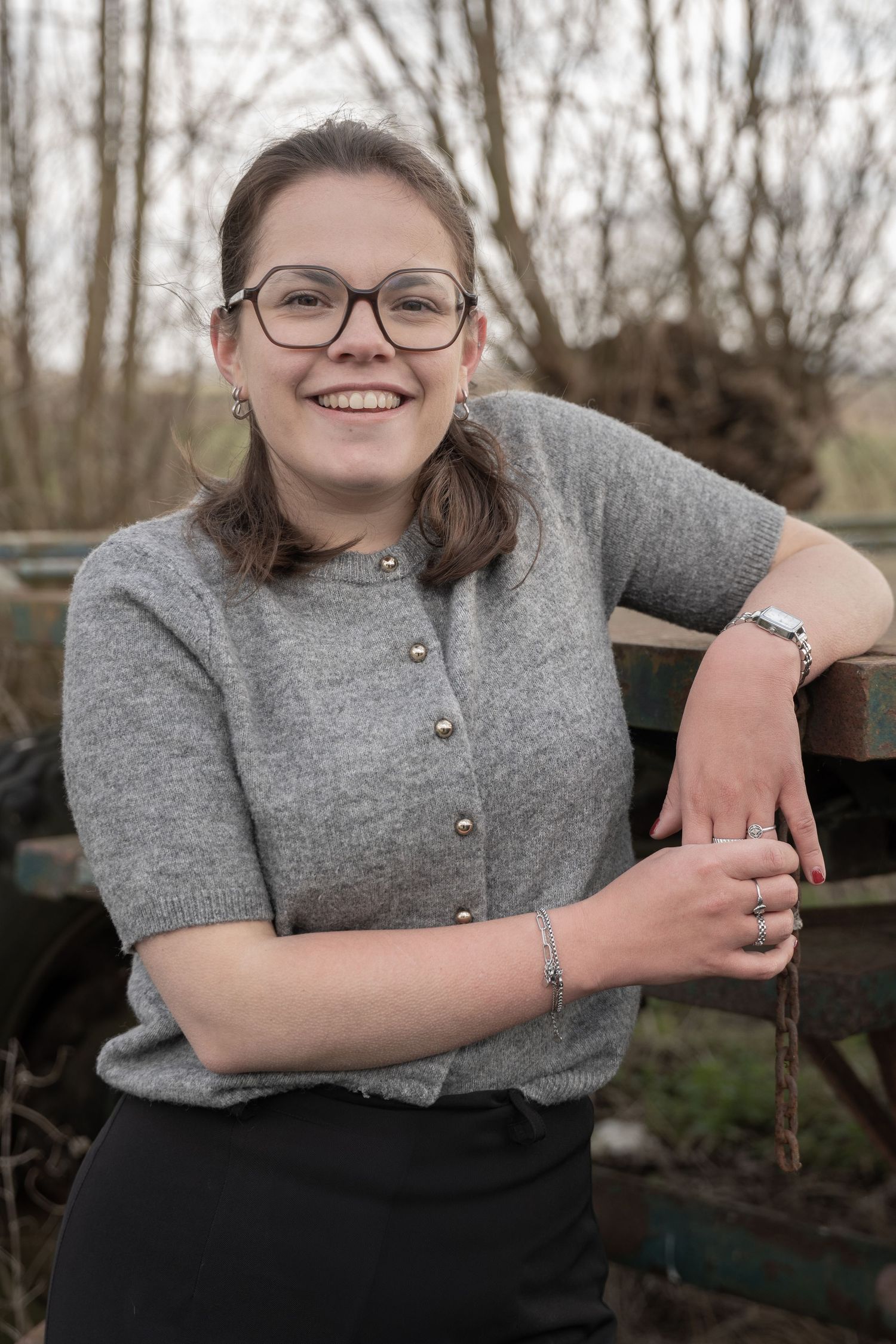 Gray knit sweater with button details photographed on rustic wooden bench outdoors.