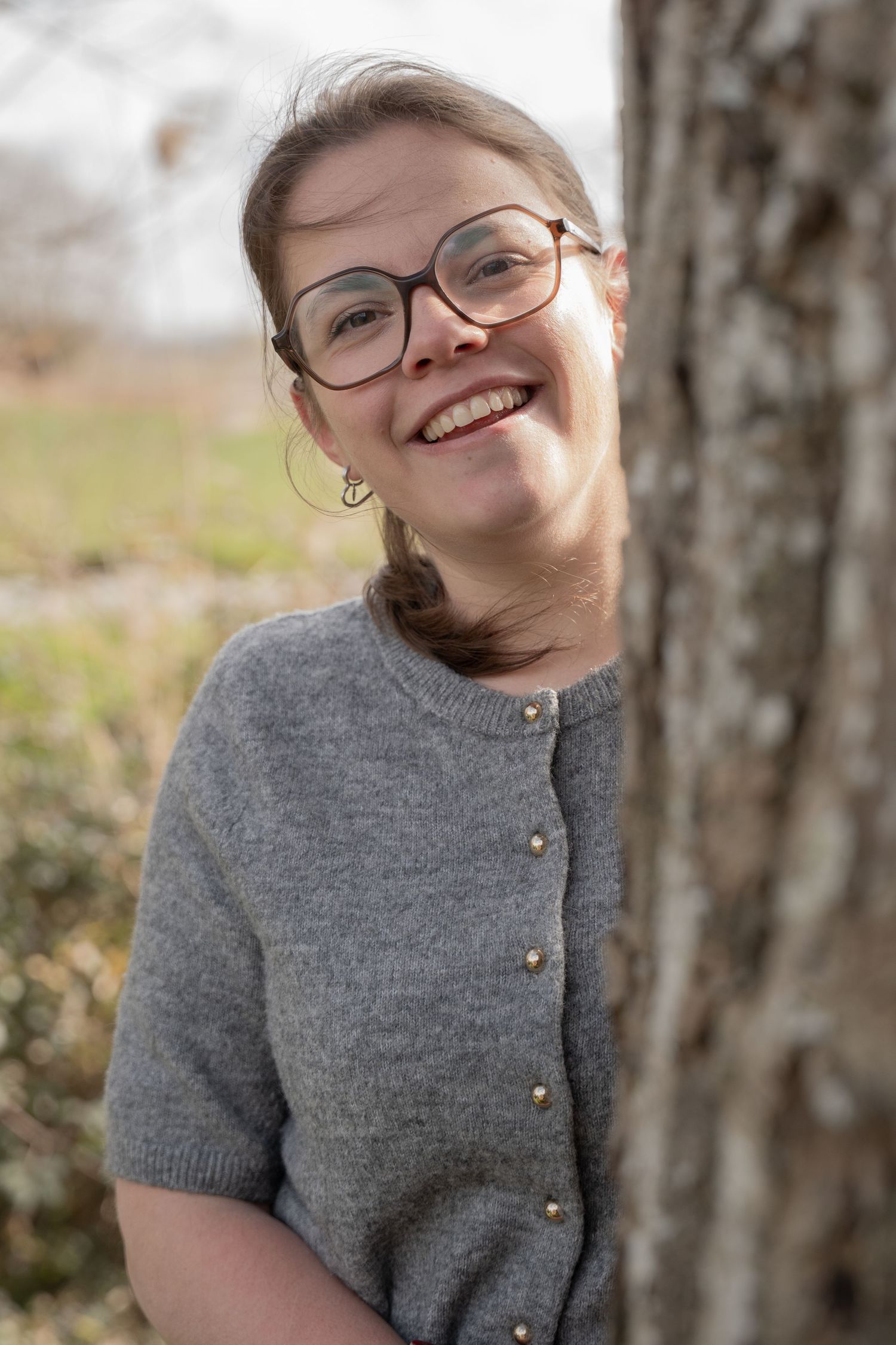 Stylish gray button-up sweater photographed against natural birch tree backdrop.