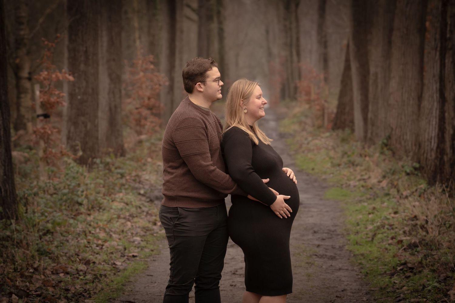 A couple embraces while walking along a misty forest path in autumn.