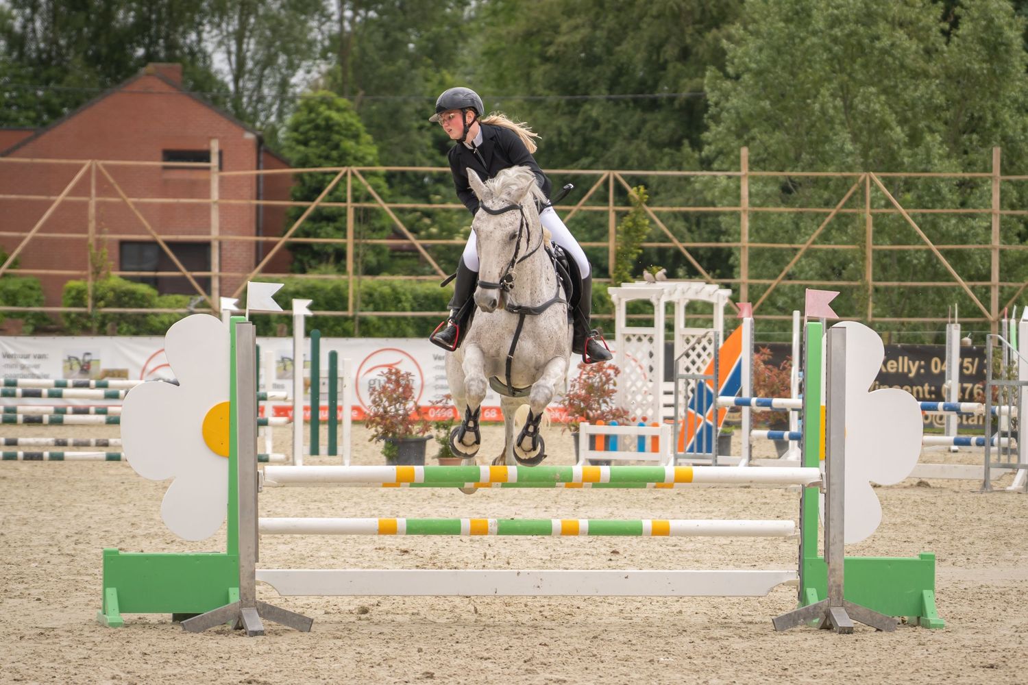 Show jumper and horse leaping over obstacle during equestrian competition.