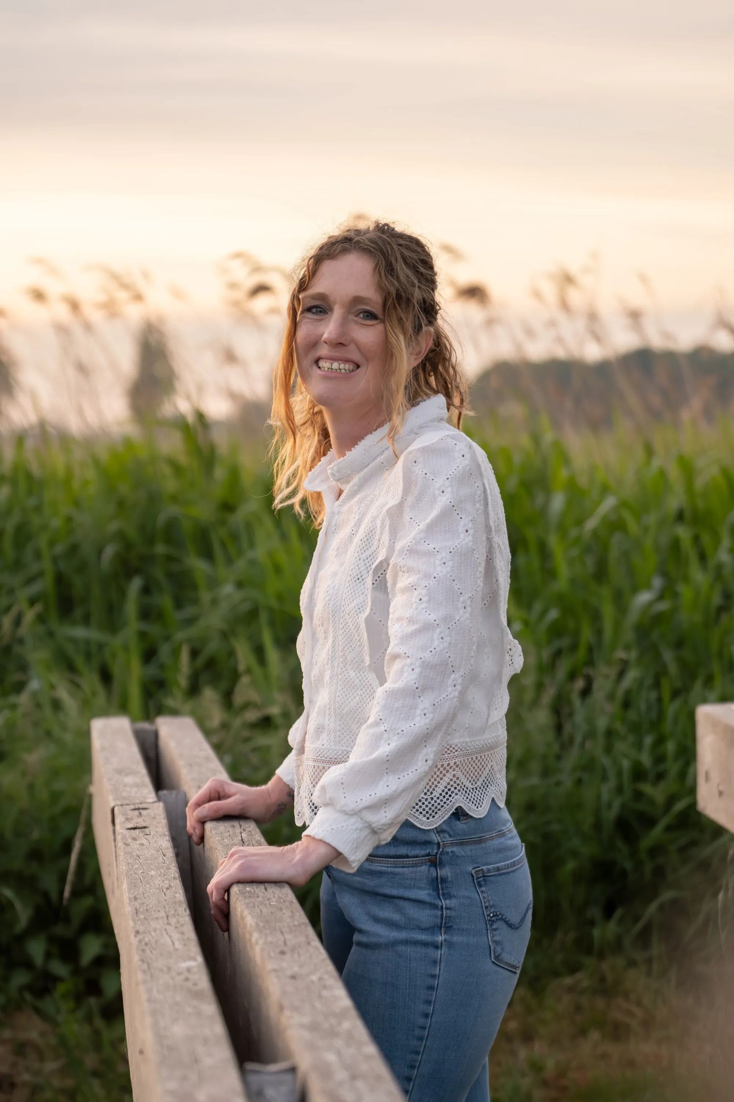 Outdoor portrait session at sunset near a cornfield with vintage wooden fence.