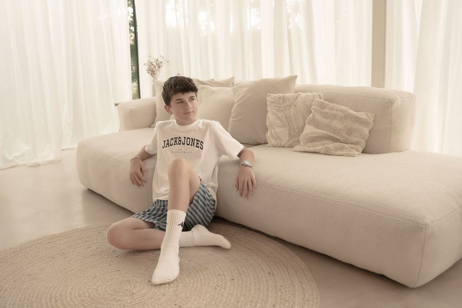 Person lounging comfortably on a white couch in a minimalist living room interior.